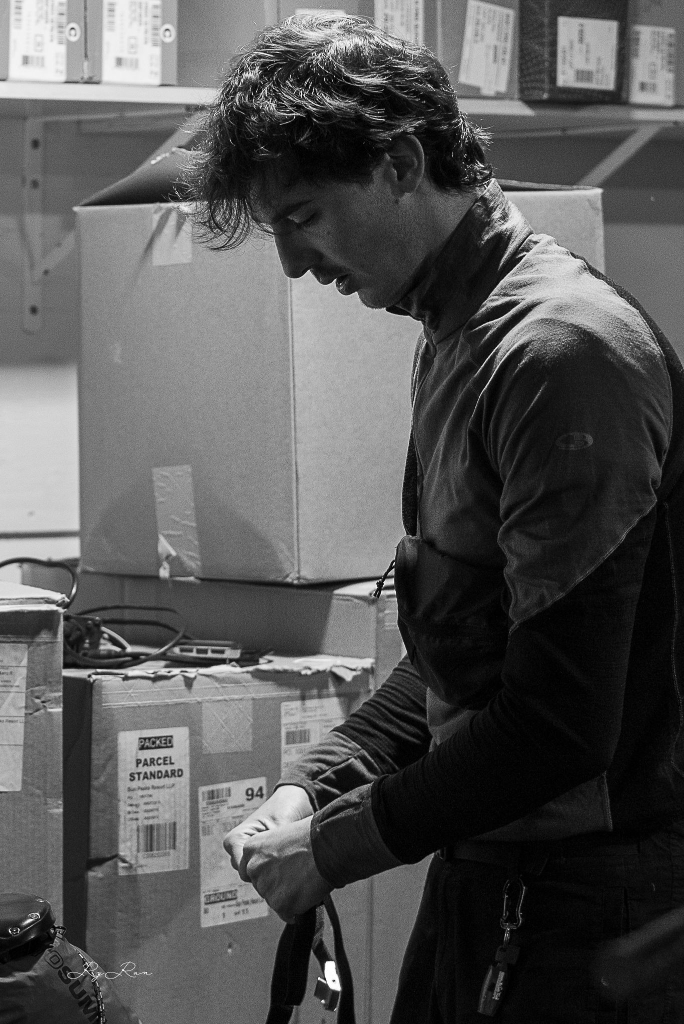 Person in black sorting packages in a warehouse storage room.