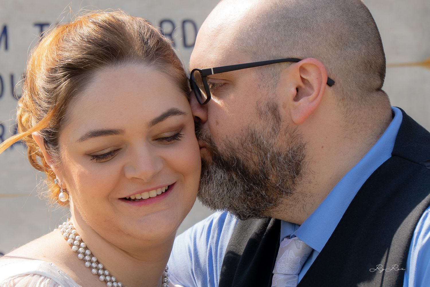 An intimate wedding portrait moment against a stone wall background.