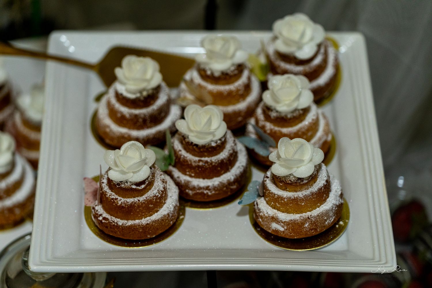 Mini layered cakes with white frosting arranged on a white serving platter.