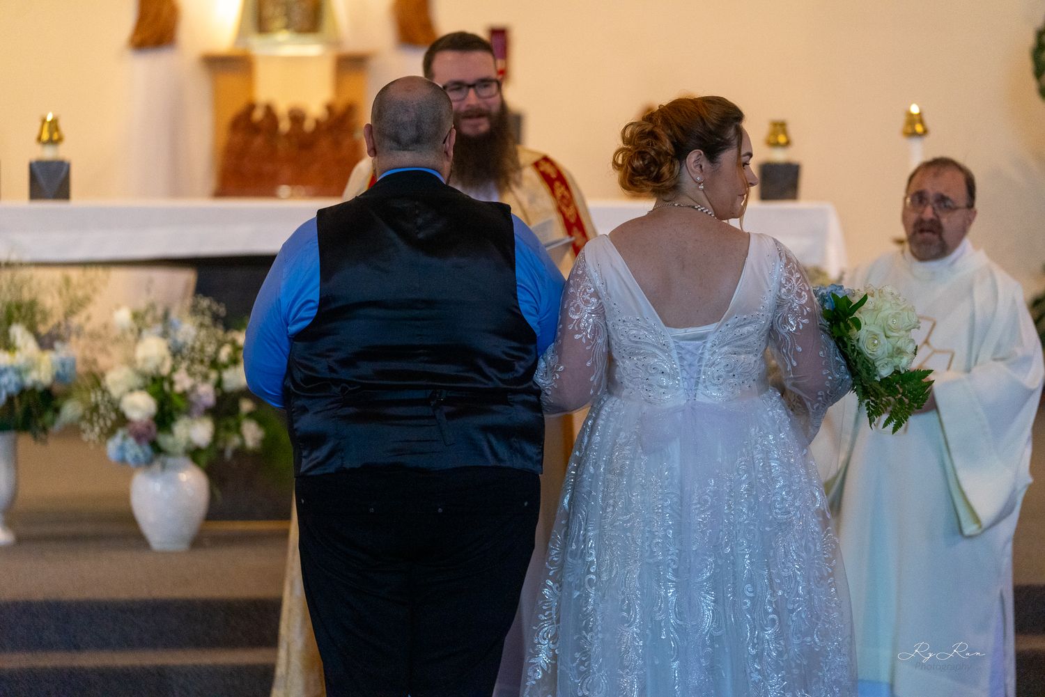 Back view of a wedding ceremony taking place at the altar with floral decorations.