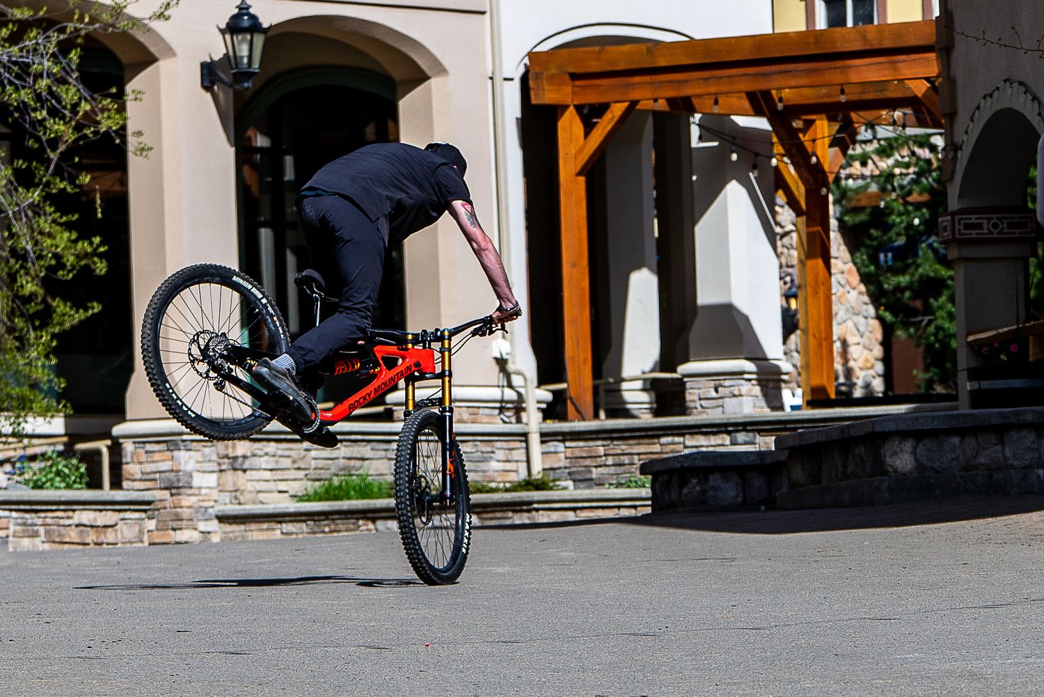 BMX rider performing a stunt trick on stairs near an arched entrance with wooden beams.