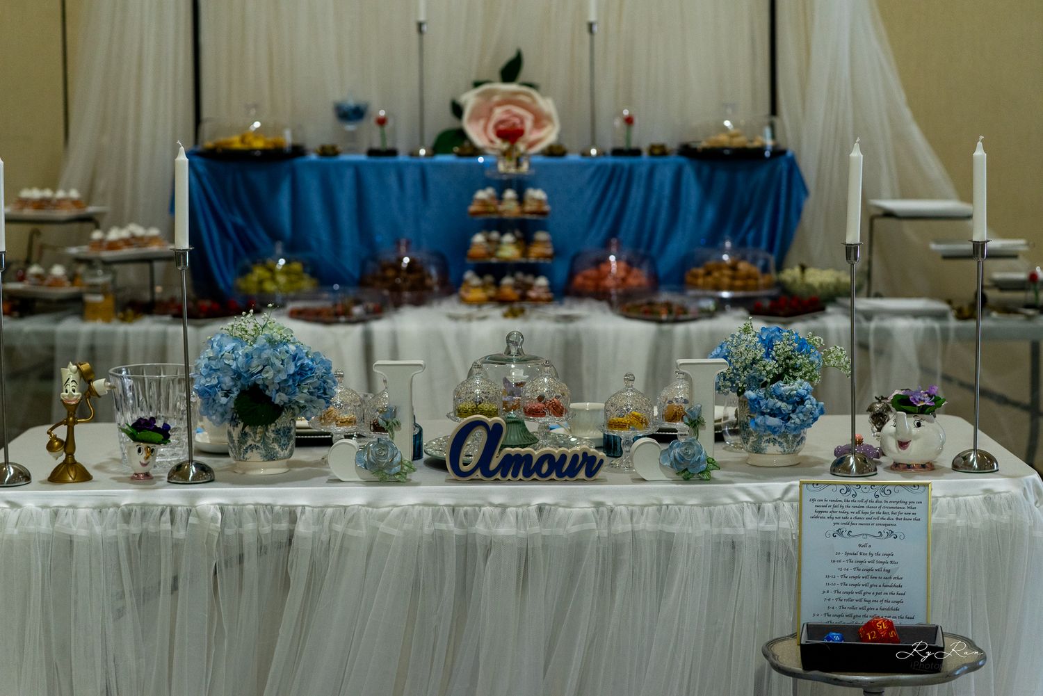 Wedding dessert table decorated in blue and white with tiered displays and elegant candles.