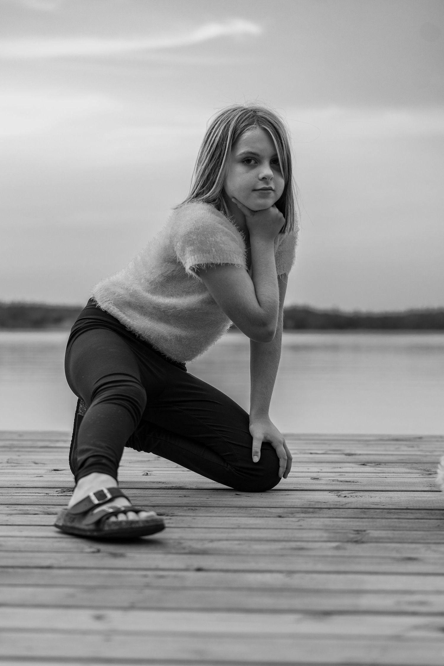 A thoughtful pose on a wooden dock overlooking a serene lake.