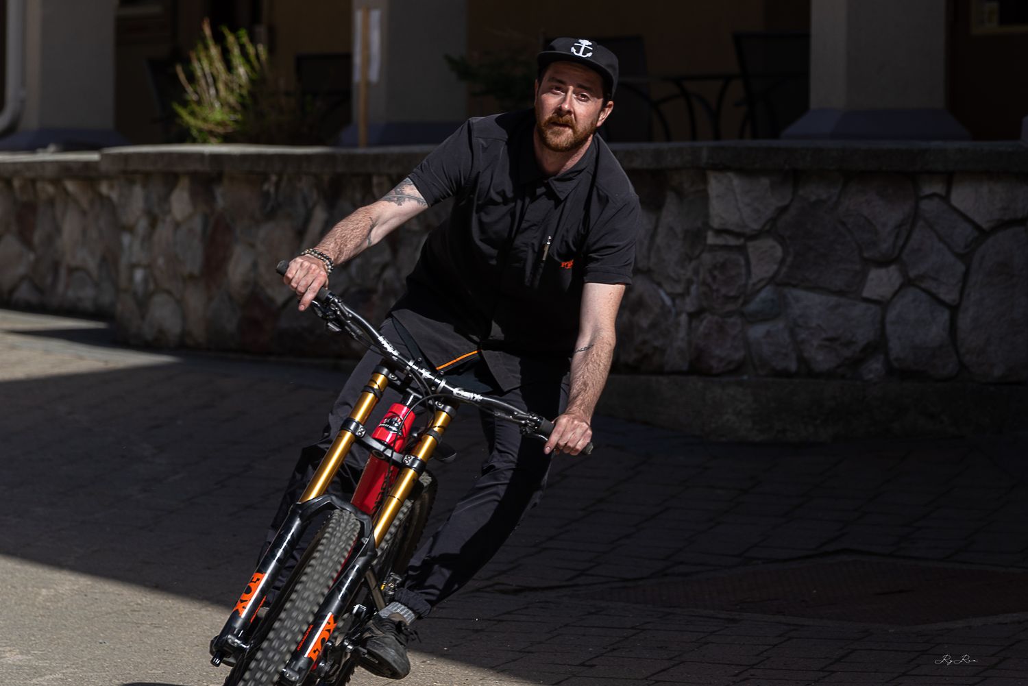 A BMX rider performing a trick on a black bike in an urban setting with stone architecture.