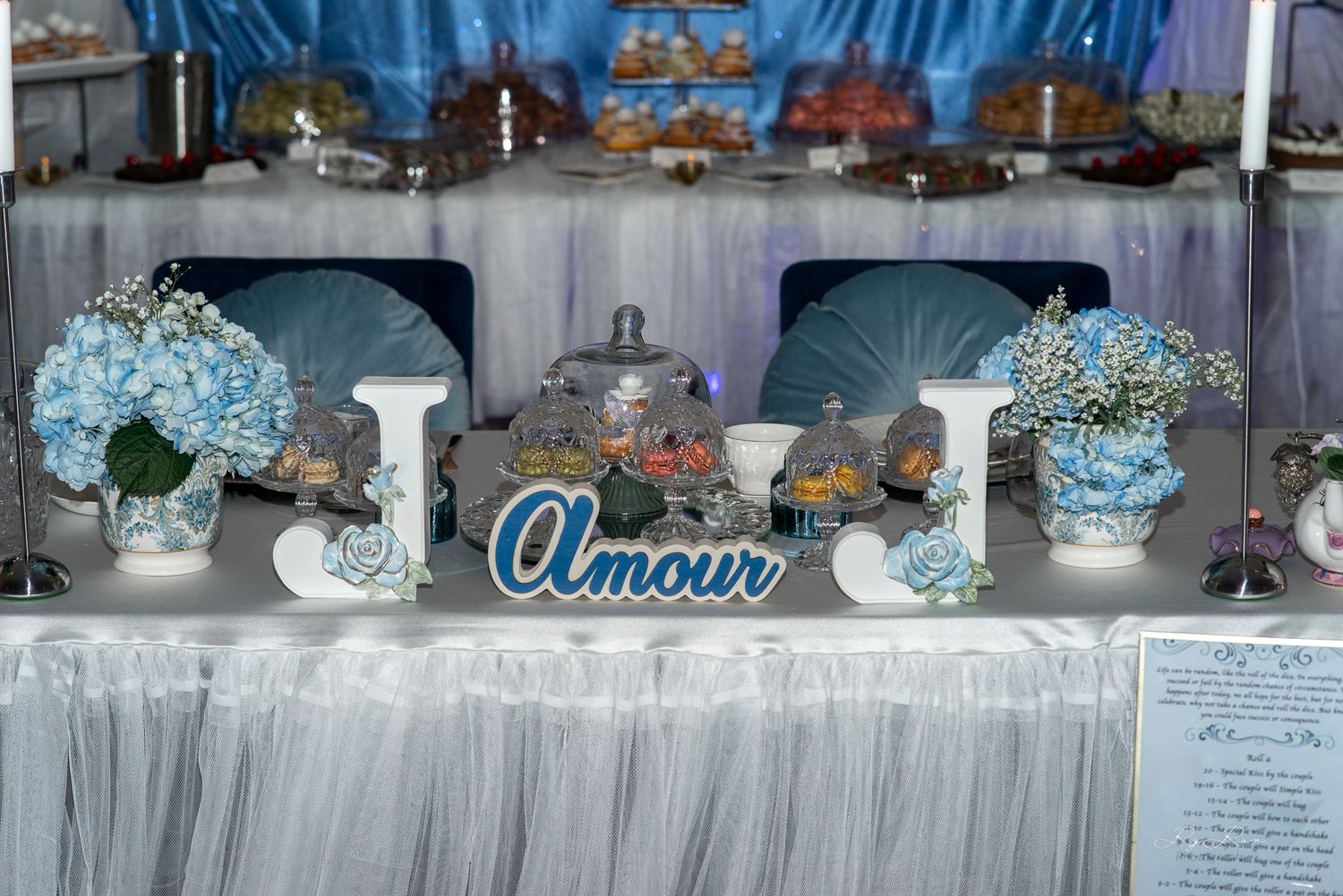 Elegant wedding reception table with blue and white decor featuring 'Amour' sign and floral arrangements.