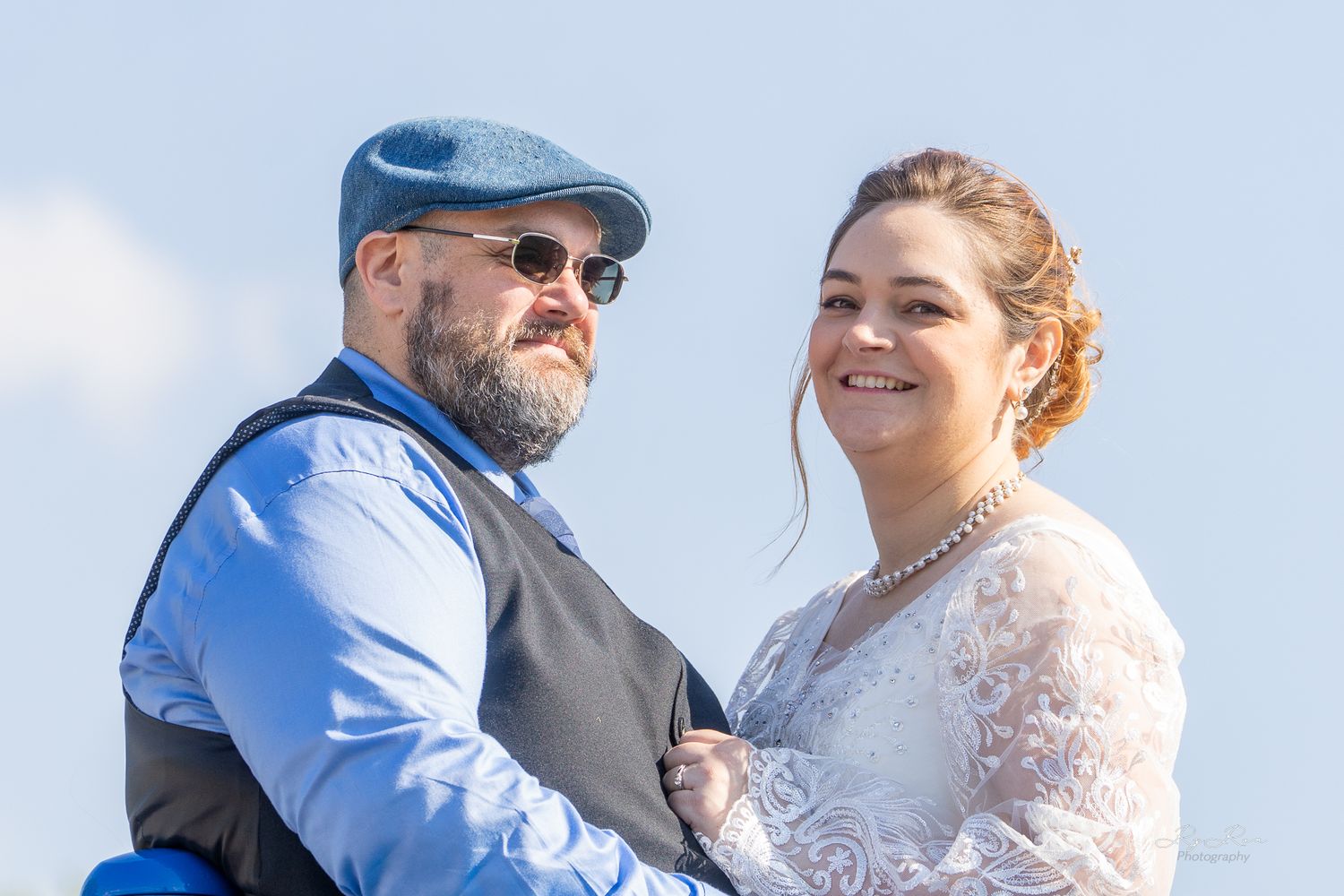 A couple shares a tender moment together outdoors on a bright sunny day.