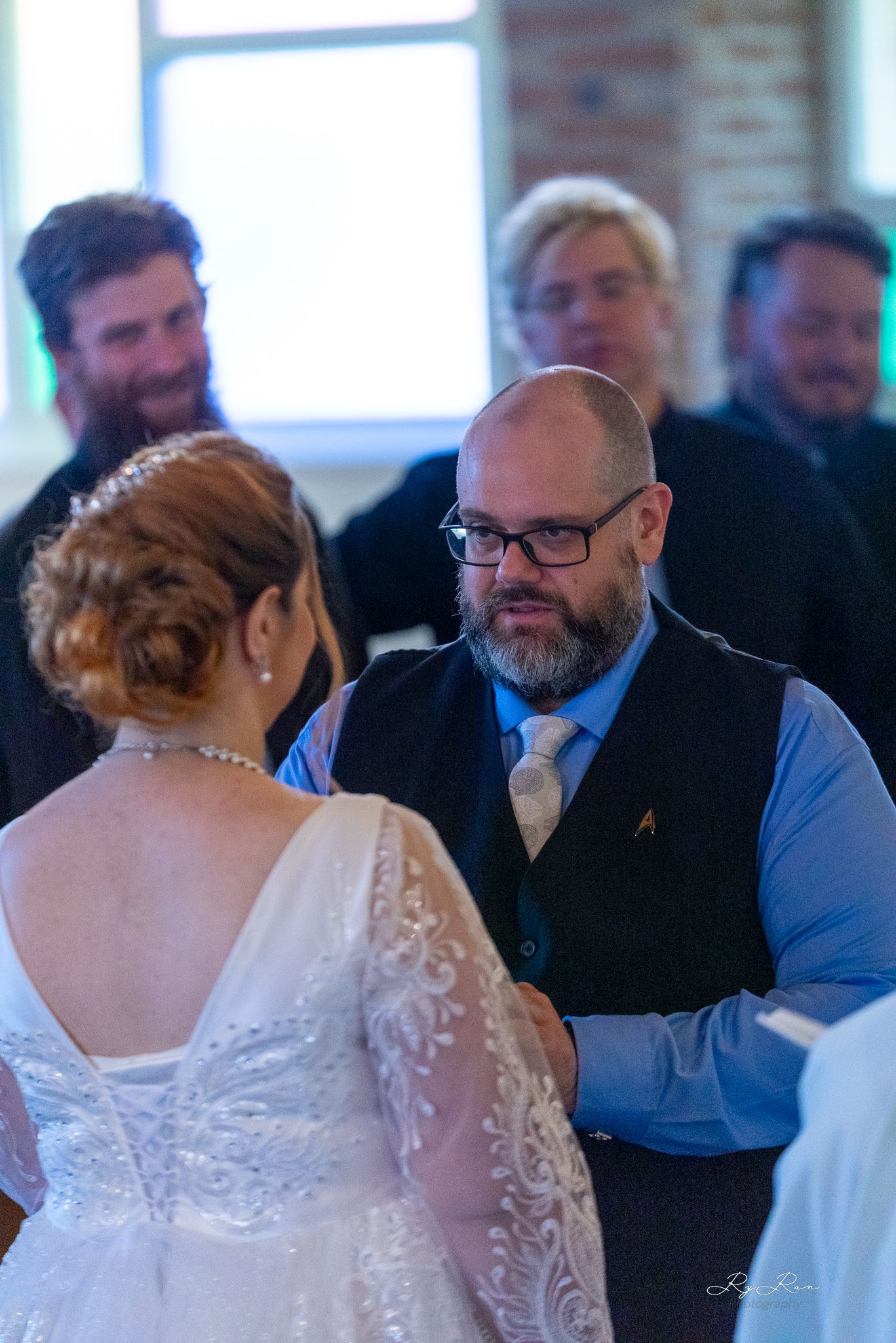 A couple shares a tender moment during their wedding ceremony while guests look on.