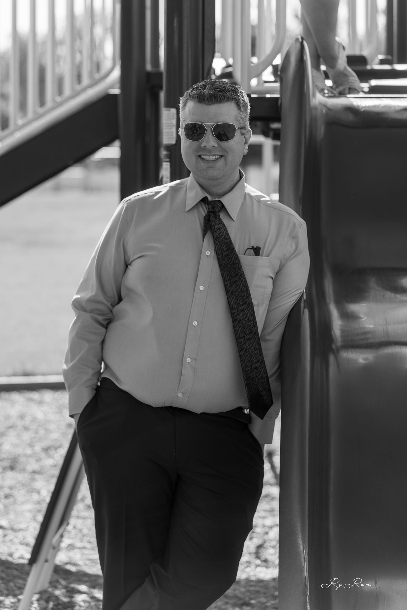 A person in formal business attire poses confidently at a playground setting.