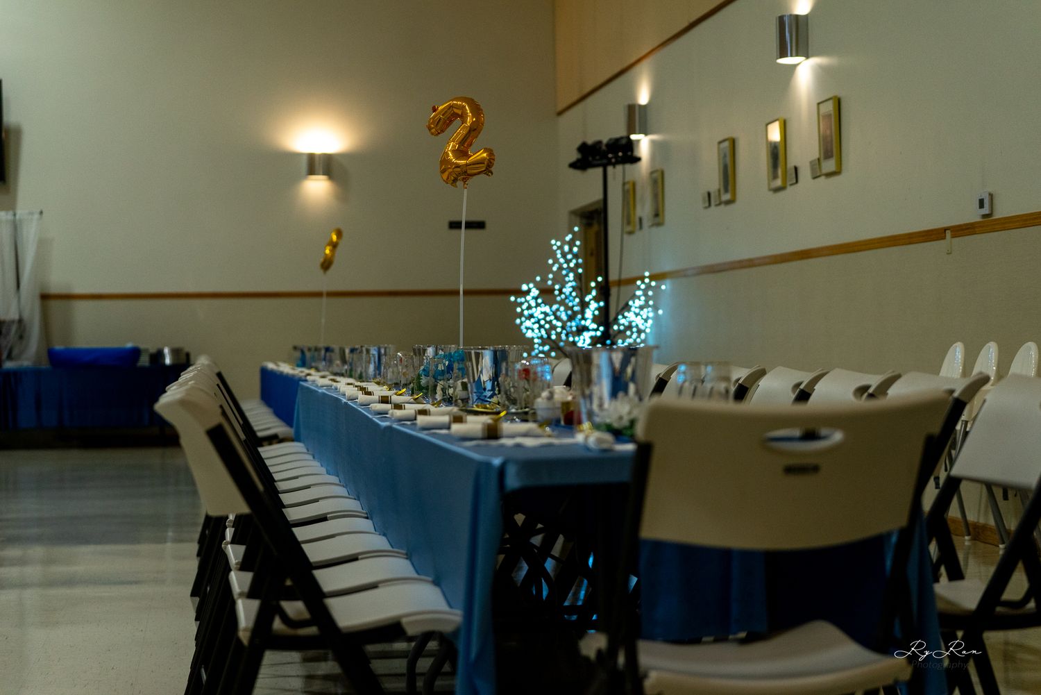 Long banquet table with blue and white decor set for formal celebration.