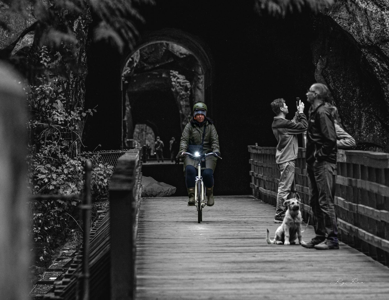 Bridge pathway through a stone tunnel with cyclists and onlookers.