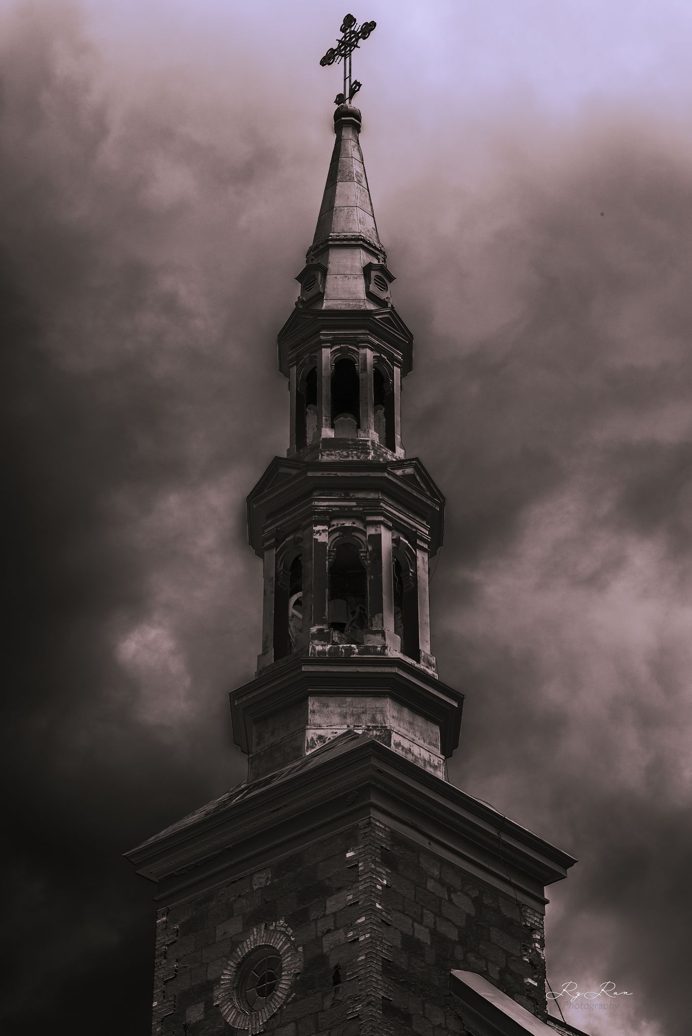 Gothic church steeple photographed against dramatic dark stormy clouds.