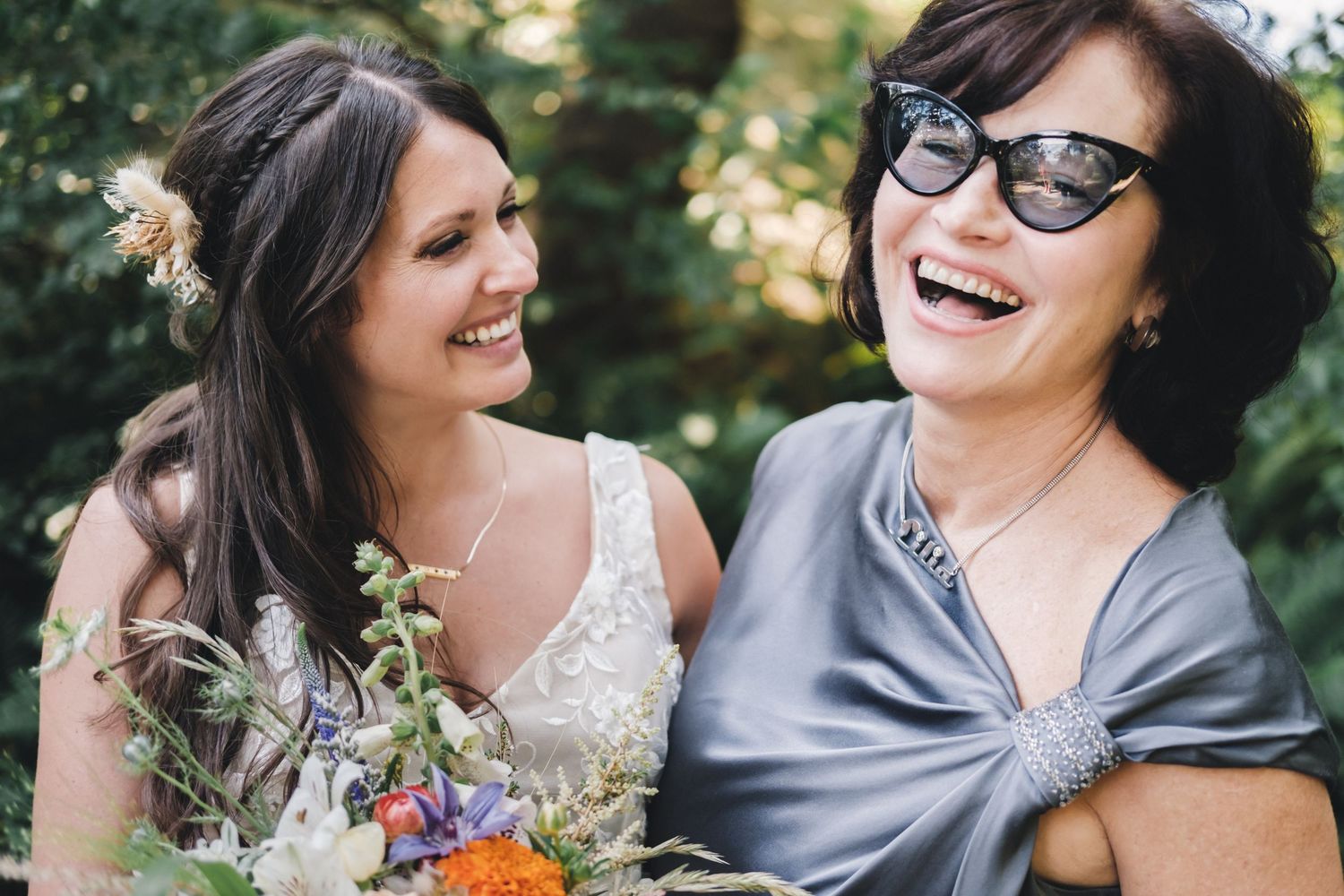 A joyful moment shared at a wedding with flowers and sunlit greenery in the background.