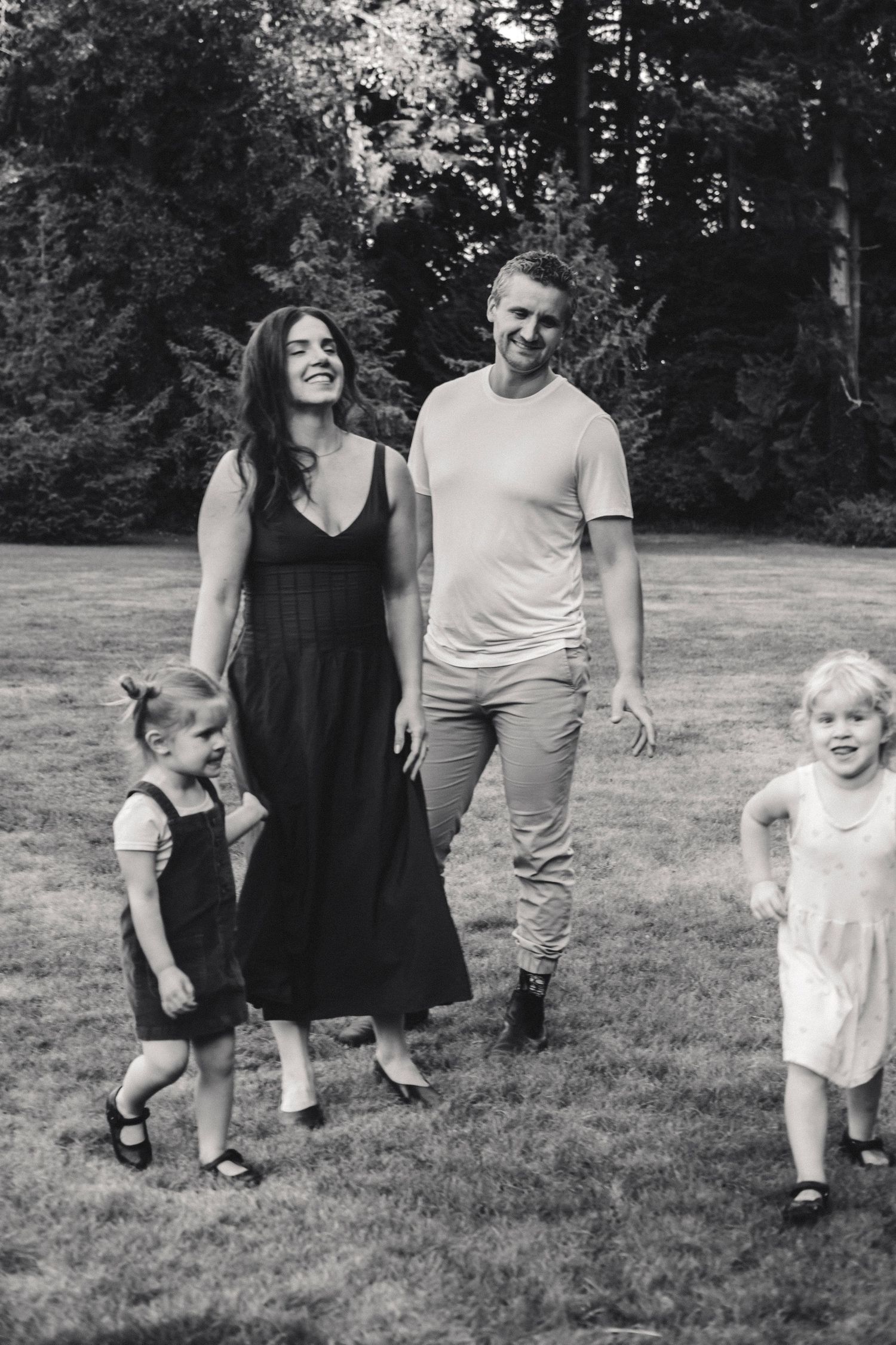 A series of black and white photos showing a family walking and playing together in a grassy outdoor setting.