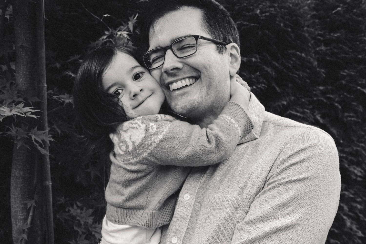 A series of black and white photos showing a couple embracing and sharing tender moments together outdoors.
