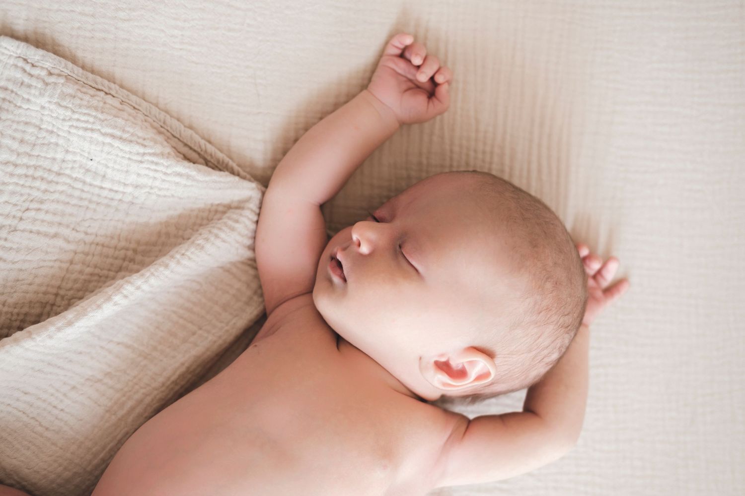 A series of connected photos showing a baby sleeping peacefully on soft white bedding.