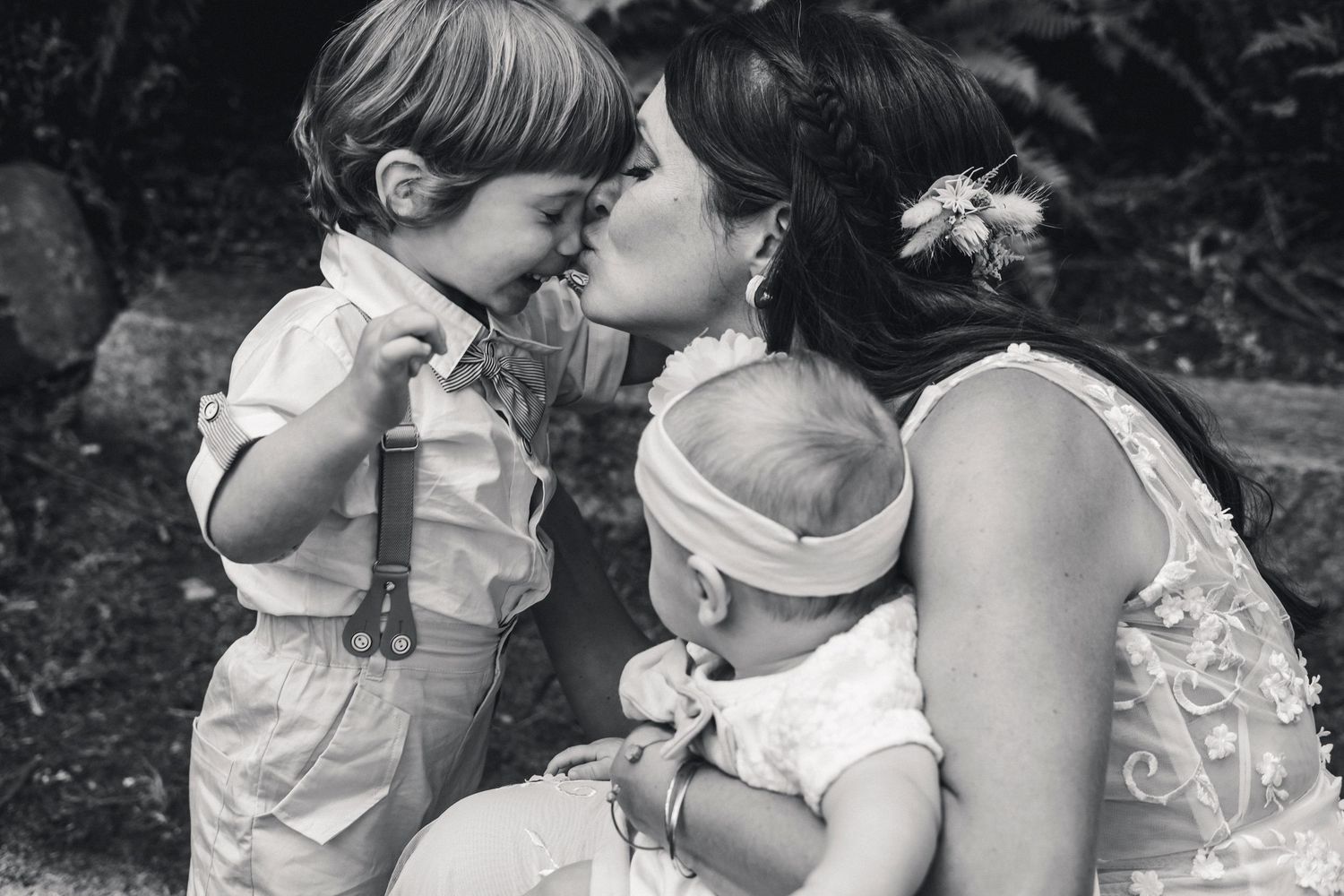 Black and white portrait of tender moment between mother and child with baby.