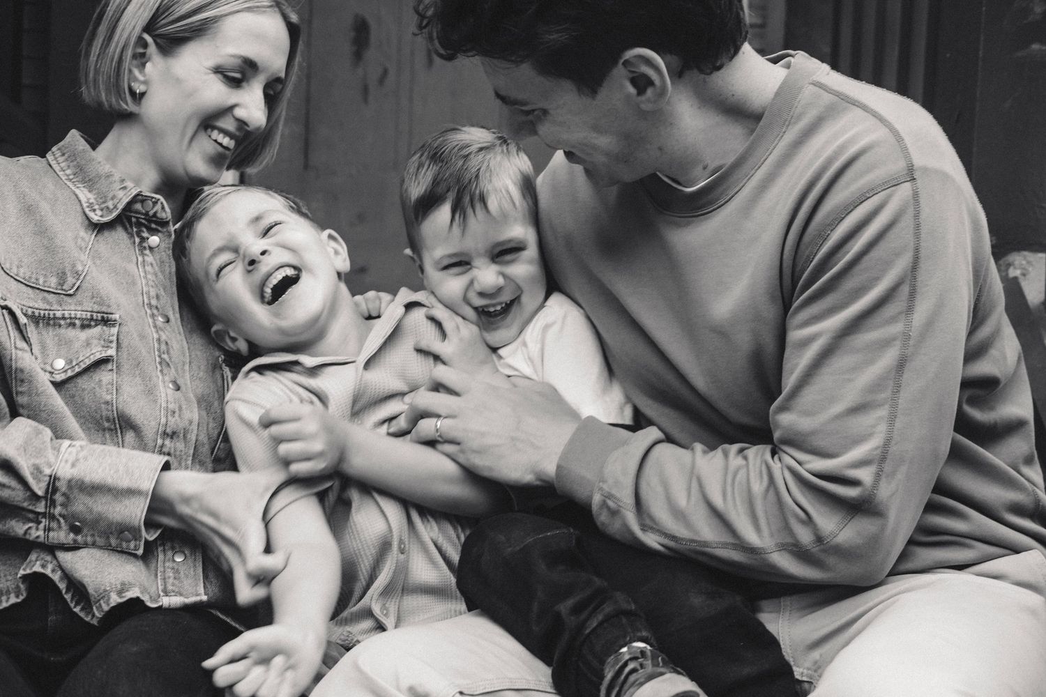 A joyful black and white candid photograph of a family sharing laughter together on a casual afternoon.