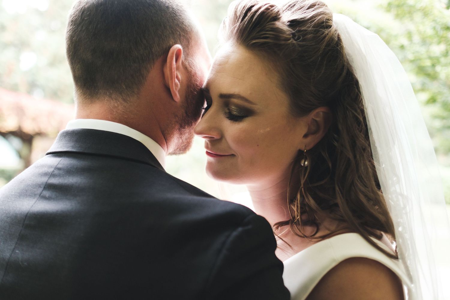 A tender moment between newlyweds at an outdoor wedding ceremony as they share an intimate embrace.