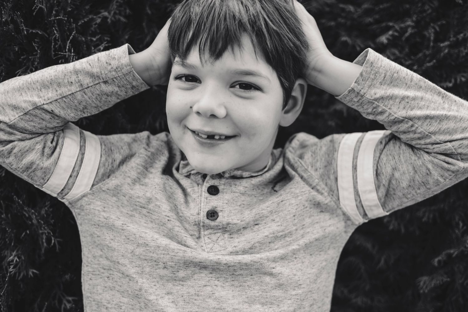 Black and white photo series showing a child in a gray sweater making playful expressions.