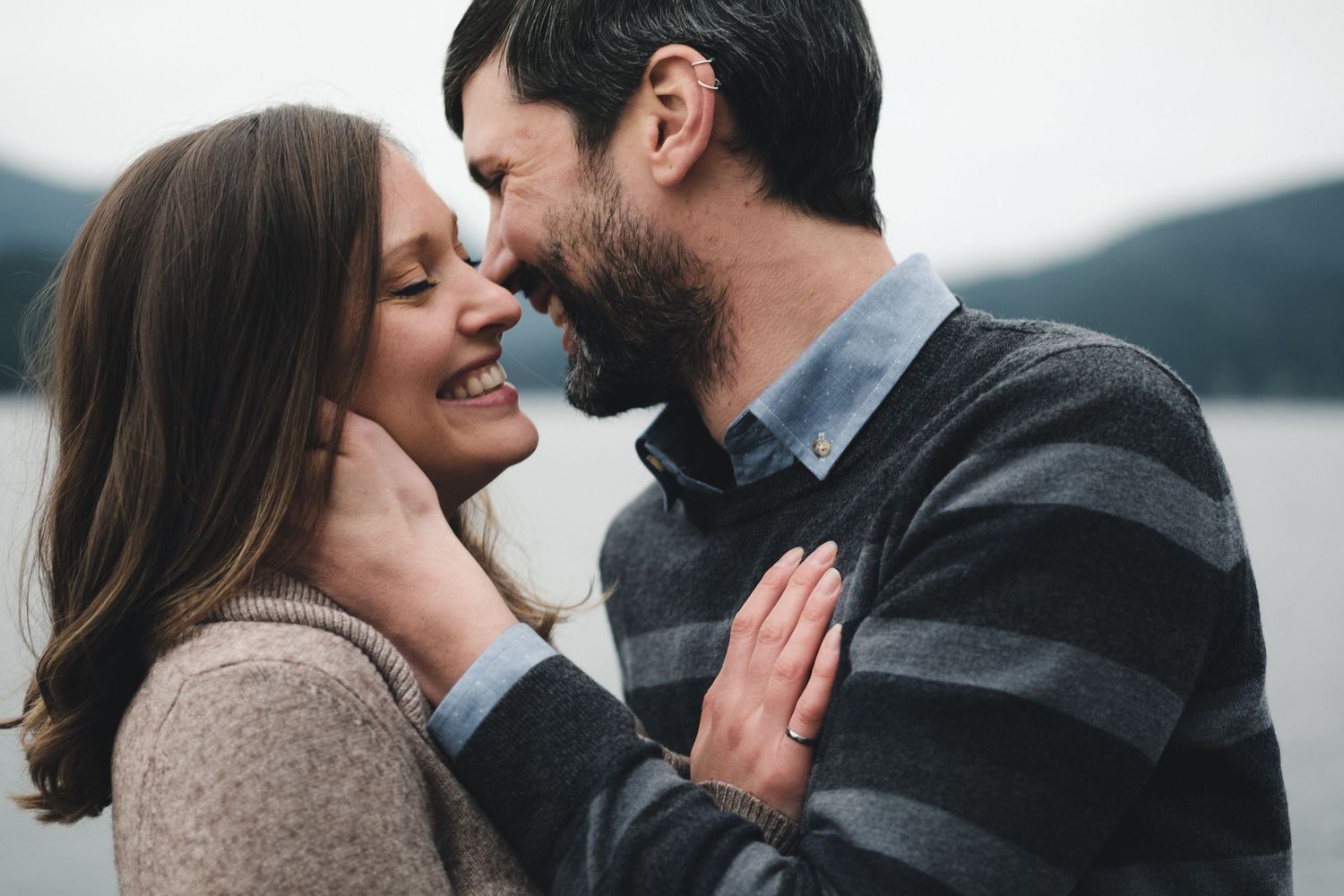 Couple shares an intimate laughing moment during romantic outdoor photoshoot.