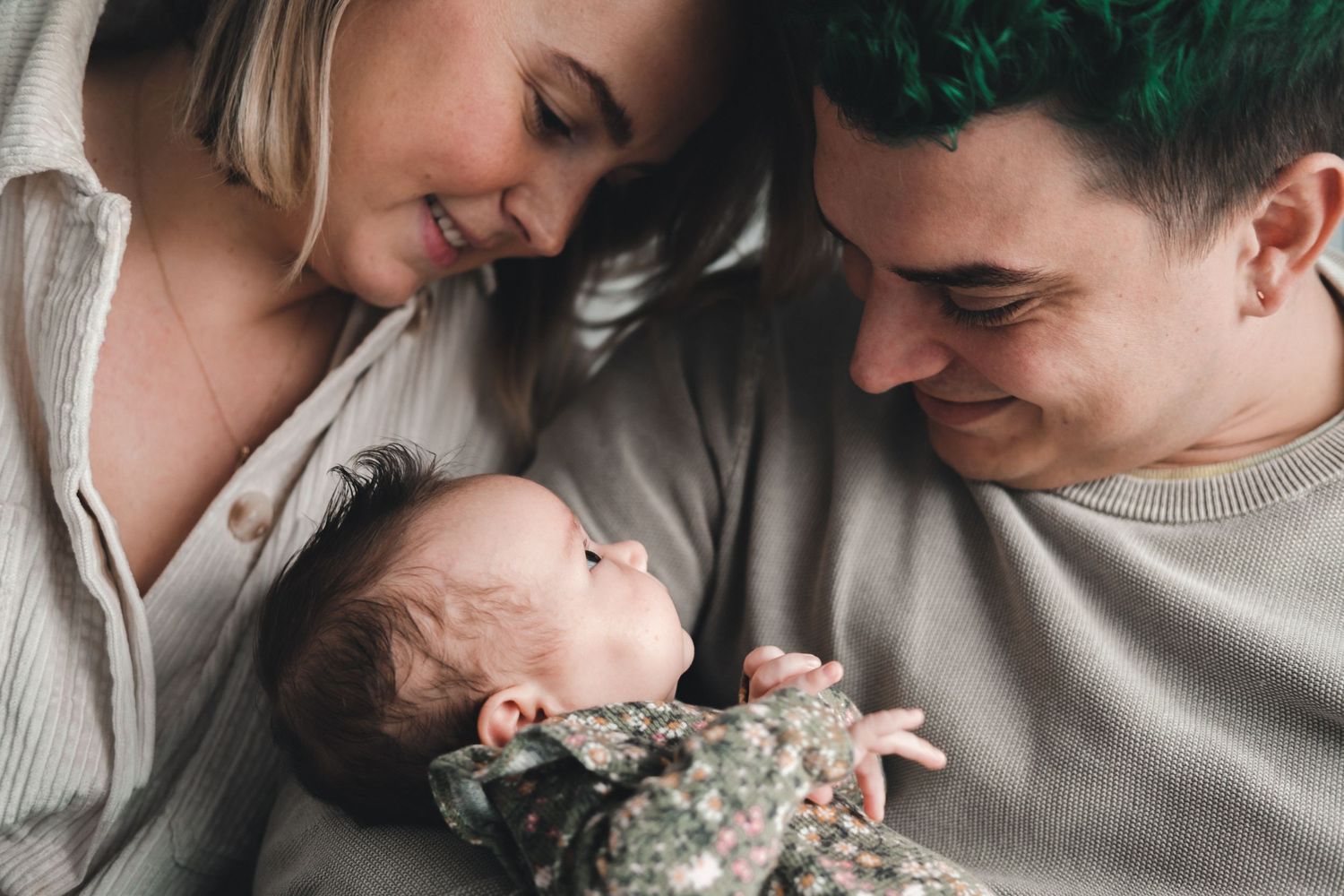 An intimate family moment with parents gazing lovingly at their newborn baby.