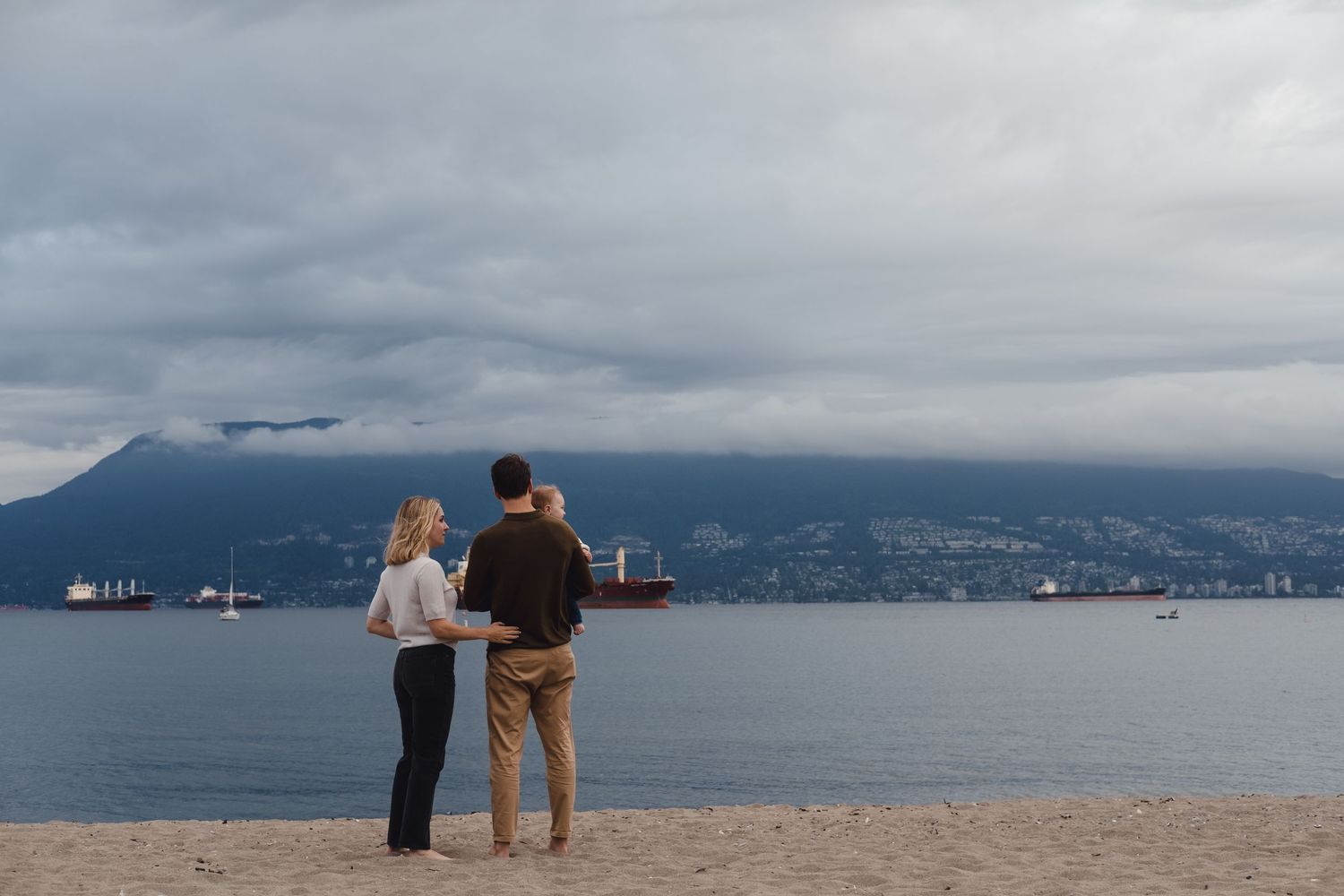 A couple stands together overlooking a misty mountain harbor view.