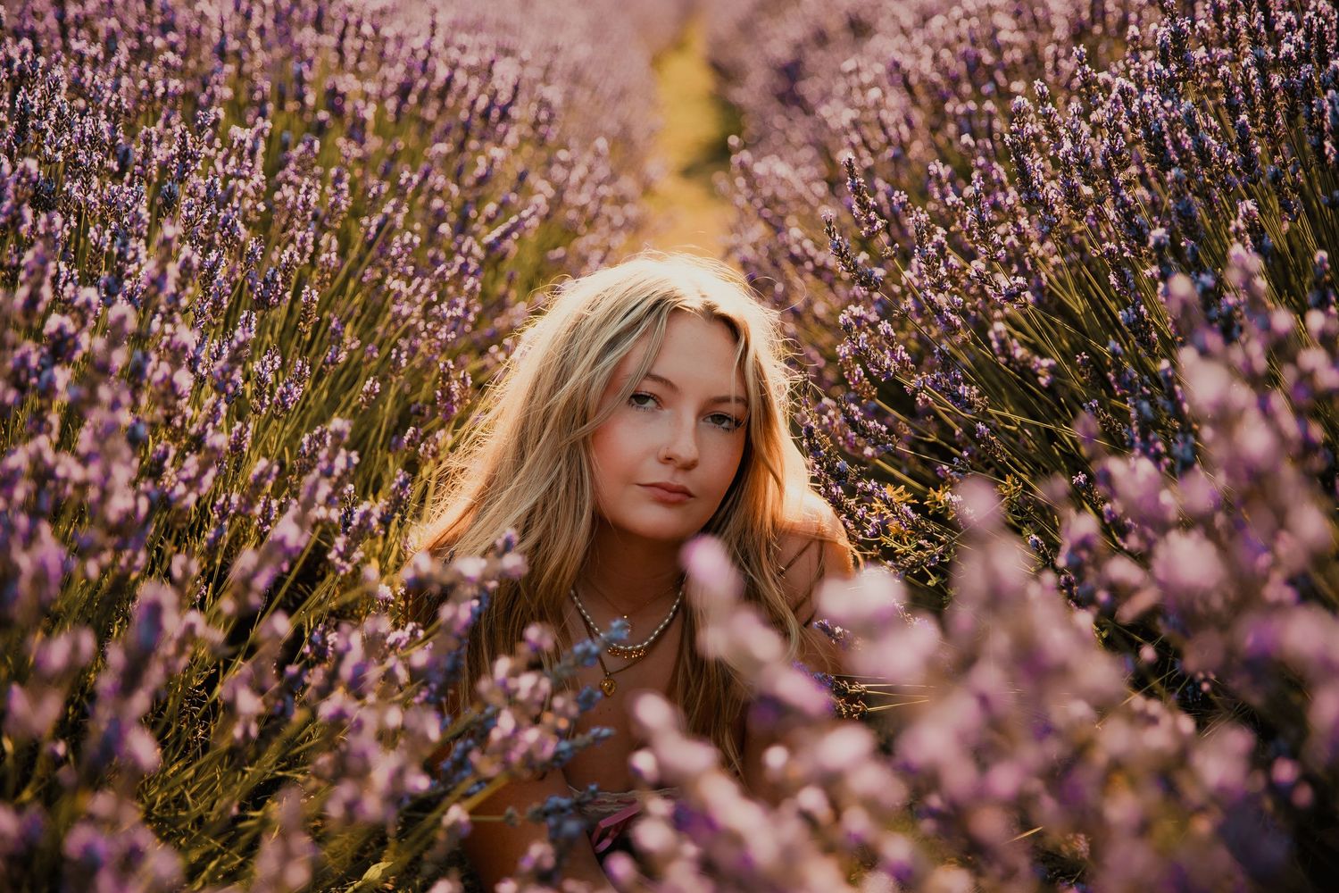 Someone poses among blooming purple lavender flowers in a field at golden hour.