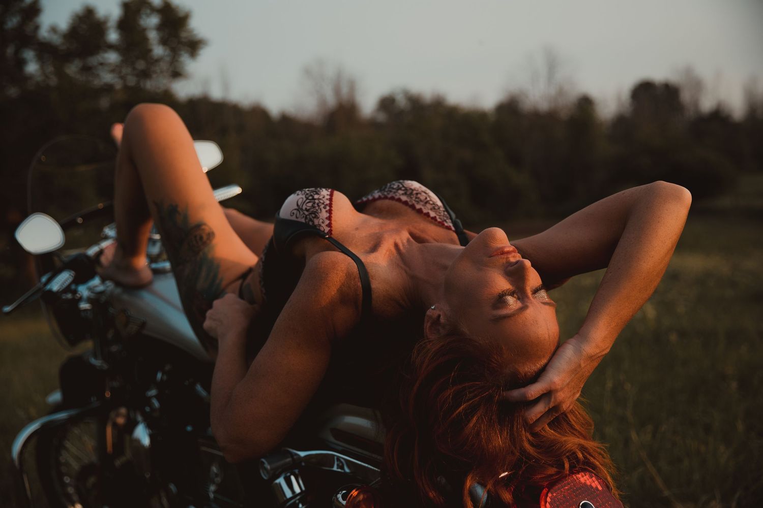 A carefree moment lounging on a motorcycle against a sunset backdrop in nature.