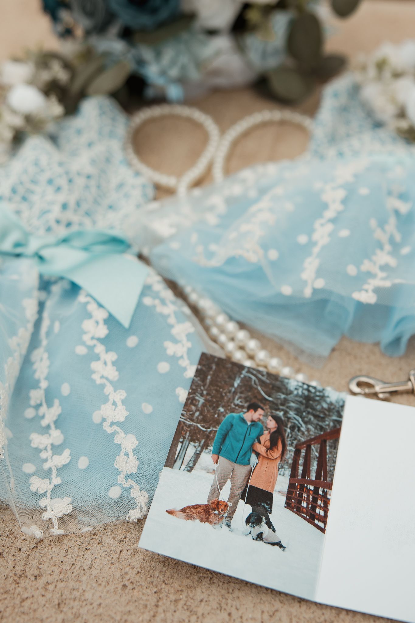 A light blue tulle dress with white floral embroidery and a nostalgic winter photo displayed against a beige background.