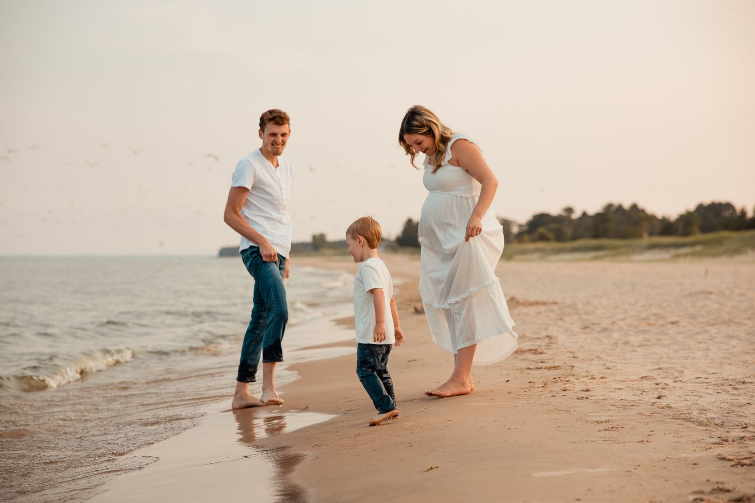 Family strolling along a sandy beach at sunset while playing and exploring together.