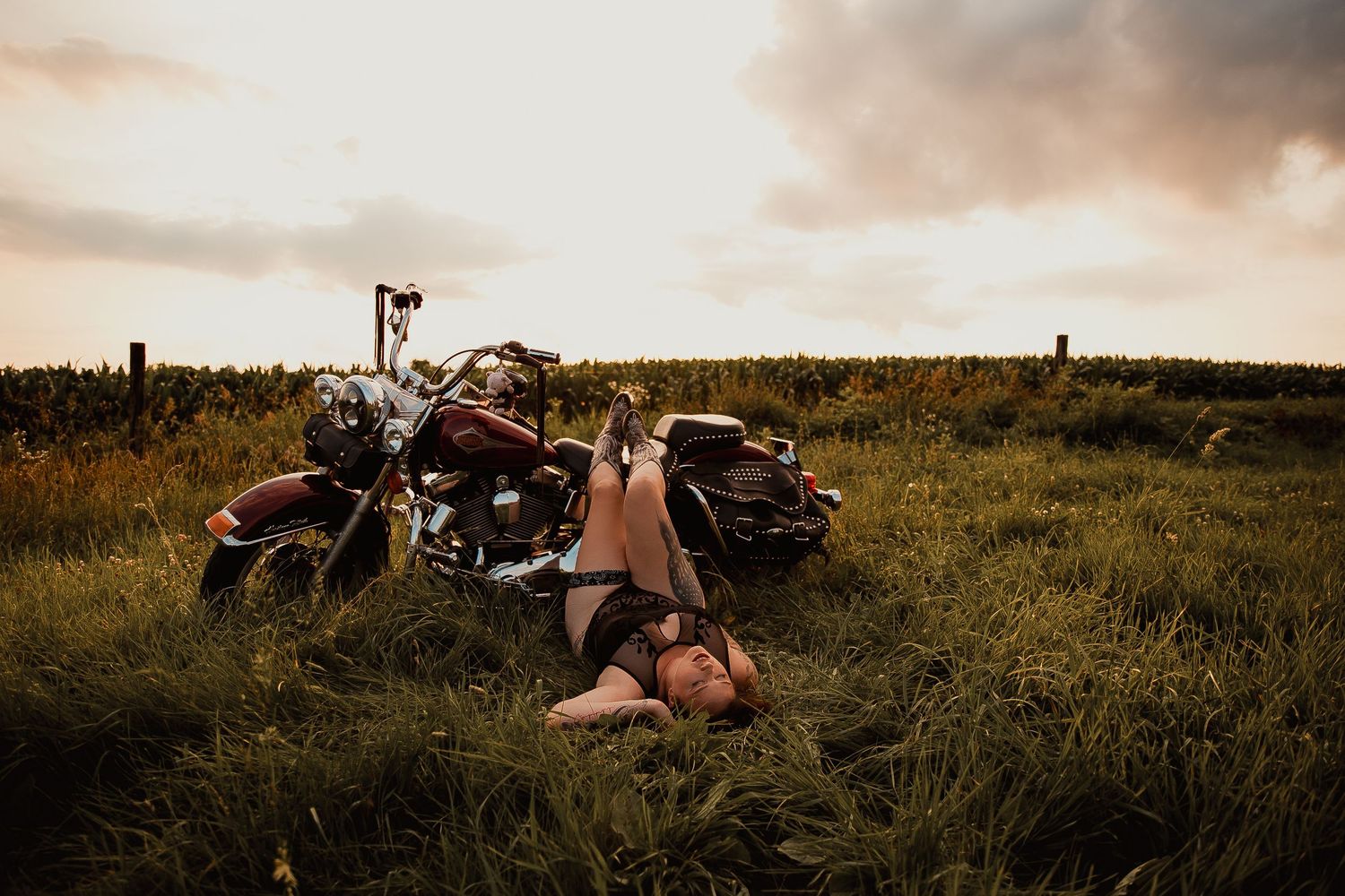 A motorcycle parked in a grassy meadow at sunset glows in warm golden light.