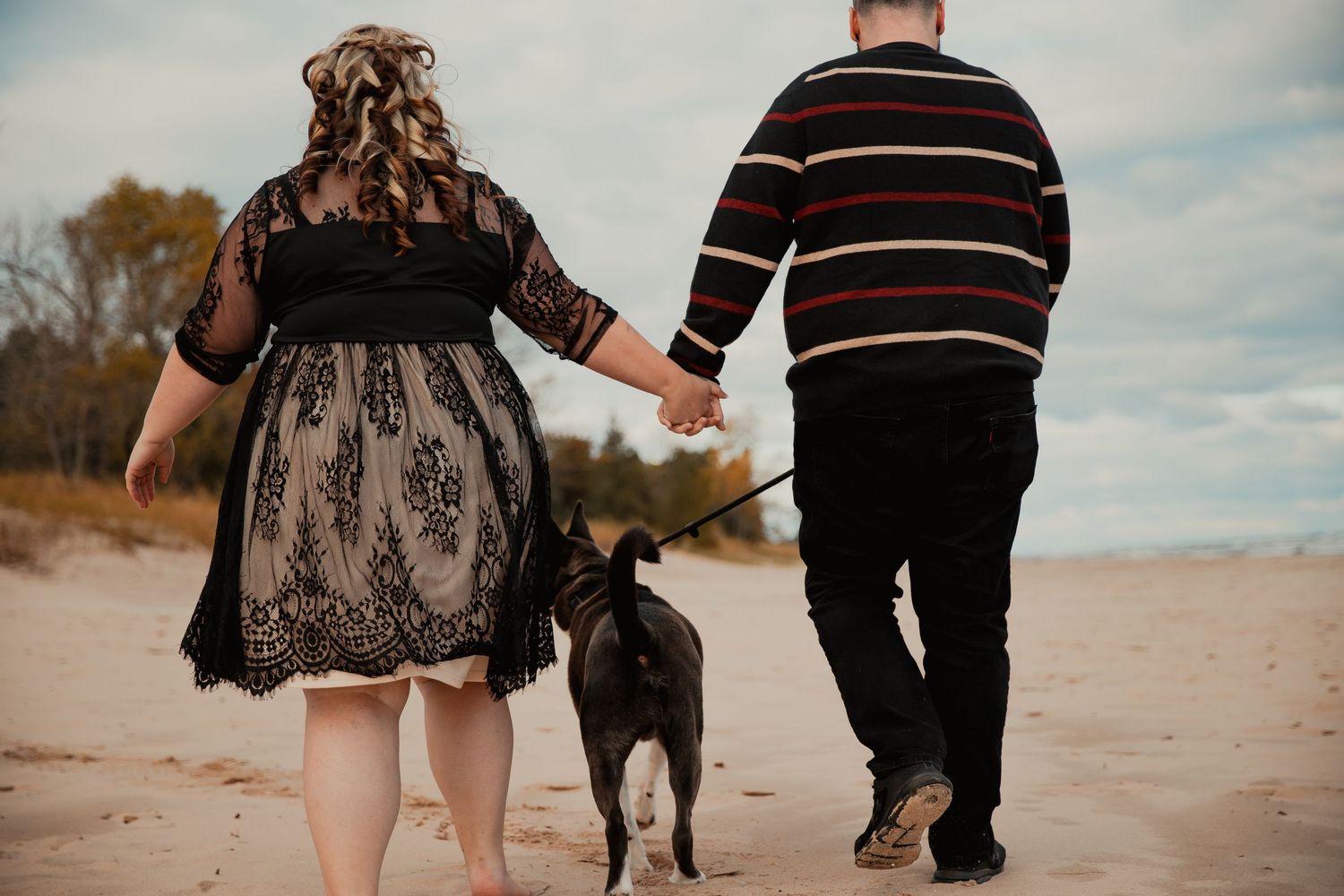 Couple walking their dog on a beach path during a cloudy day. couples engagement