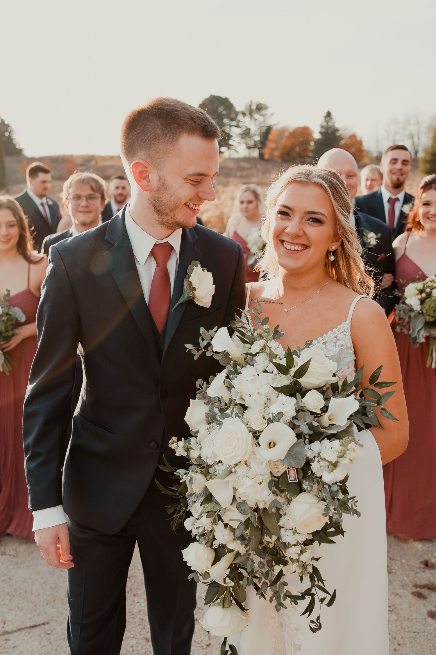 Wedding couple sharing joyful moment outdoors with bridal party in burgundy dresses. wedding