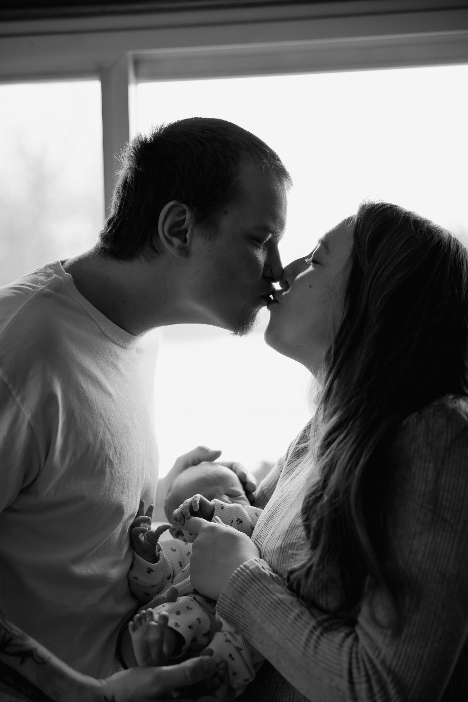 A black and white photo series showing intimate romantic moments between a couple by a window.