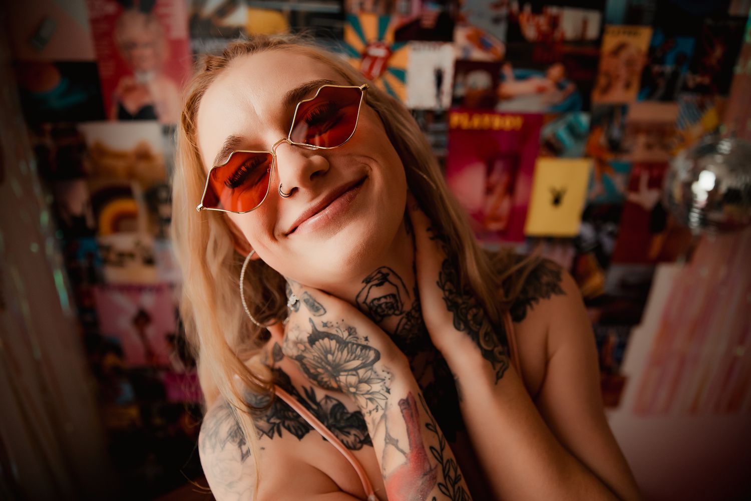 Portrait of tattooed person wearing orange sunglasses against colorful background. boudoir