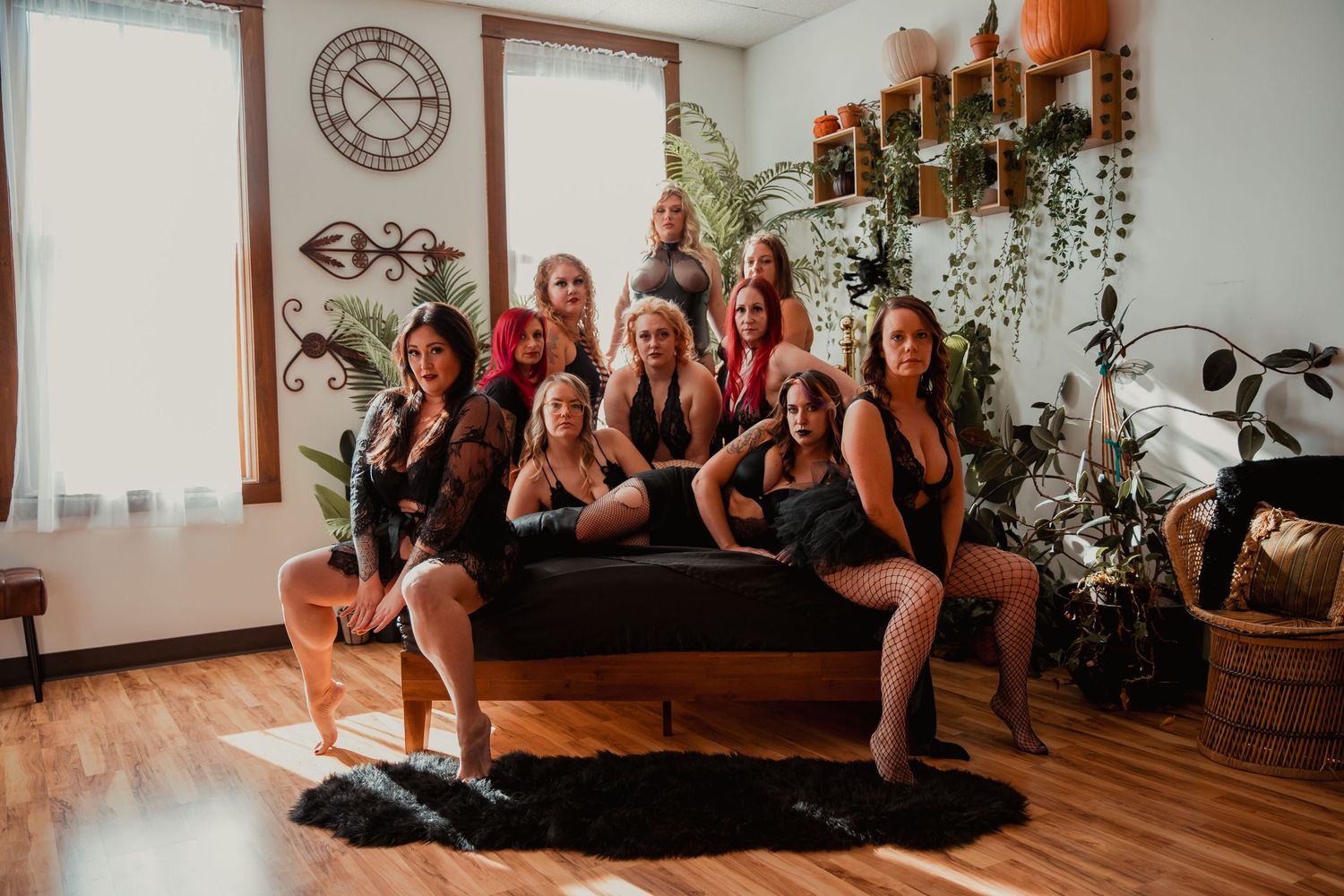 Group in matching black loungewear sitting together on a couch in a cozy living room with plants and rustic decor.