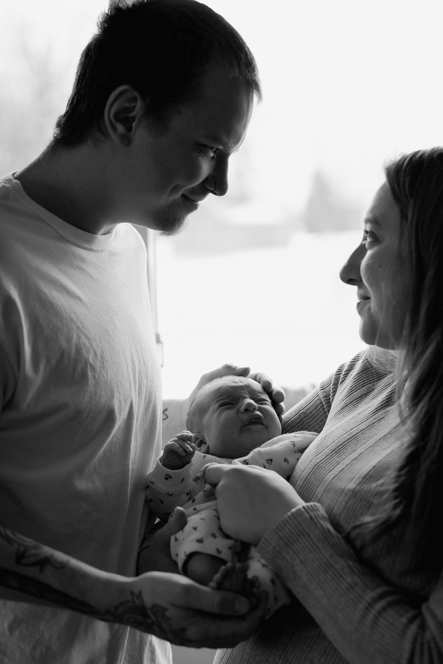 Black and white photo series showing tender moments between parent and newborn baby in hospital setting.