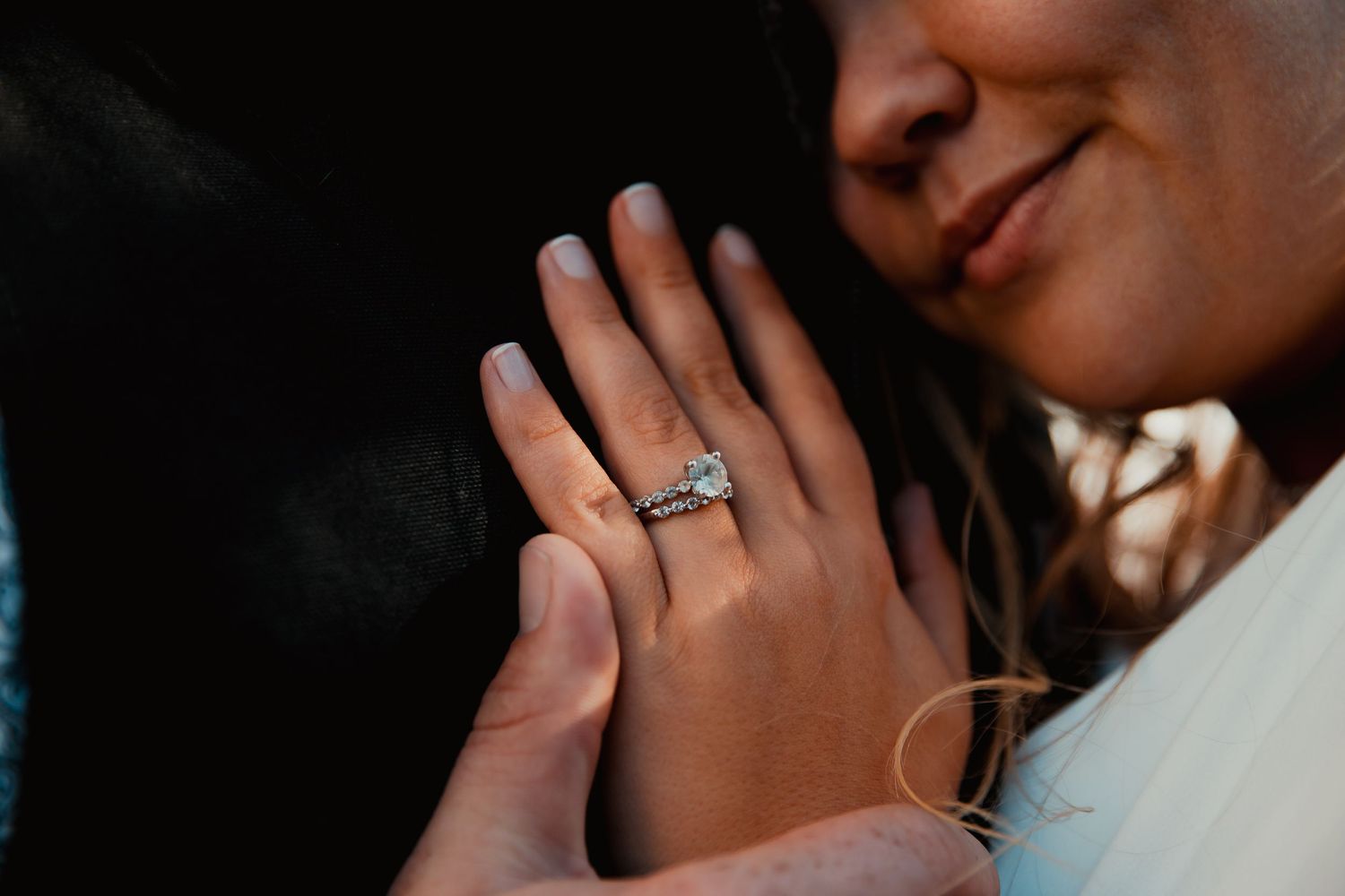Close-up of engagement ring with hands clasped together. wedding