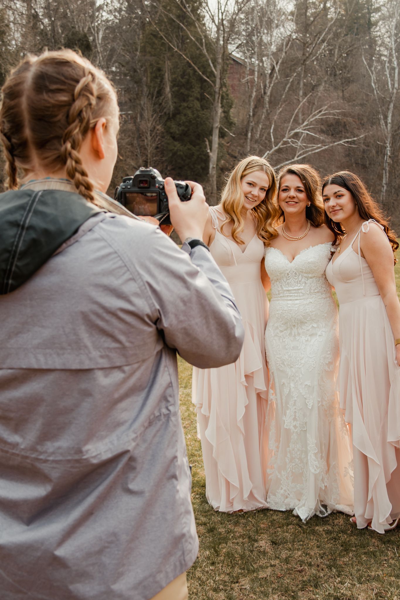 A photographer captures bridesmaids in blush pink dresses during an outdoor photo session. wedding