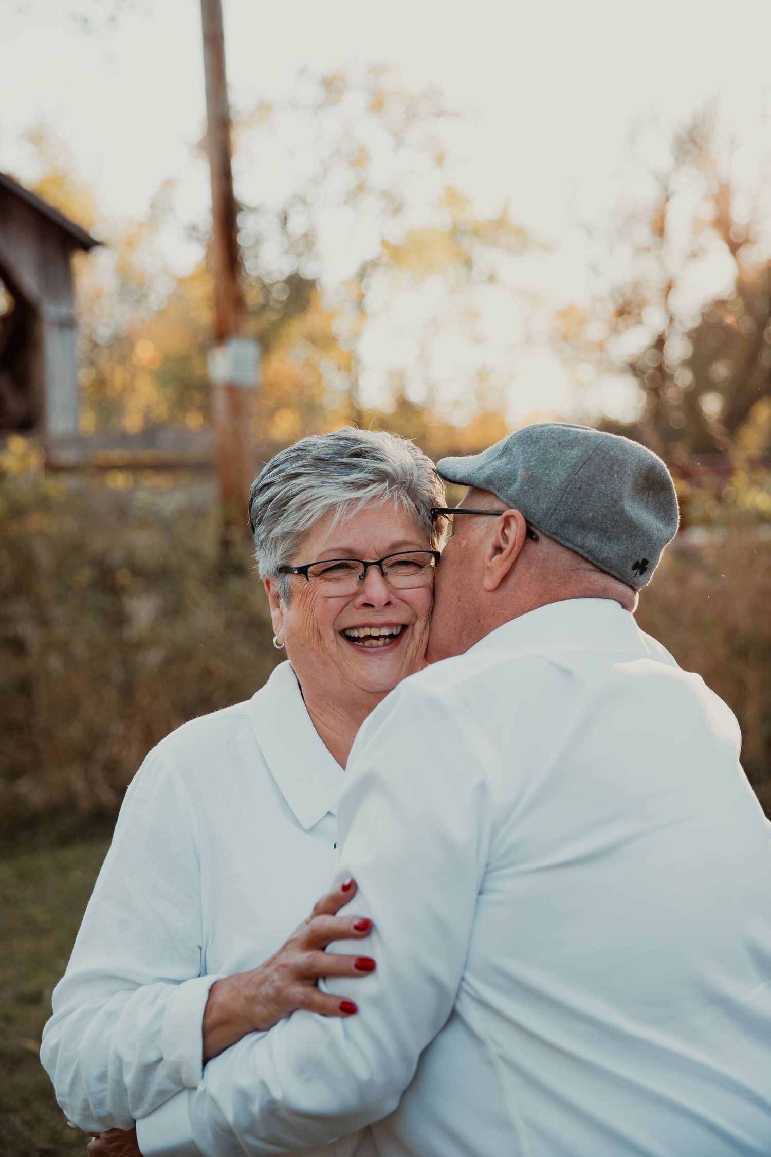 Candid moment of couple sharing laughter in white shirts during outdoor photoshoot. couples engagement