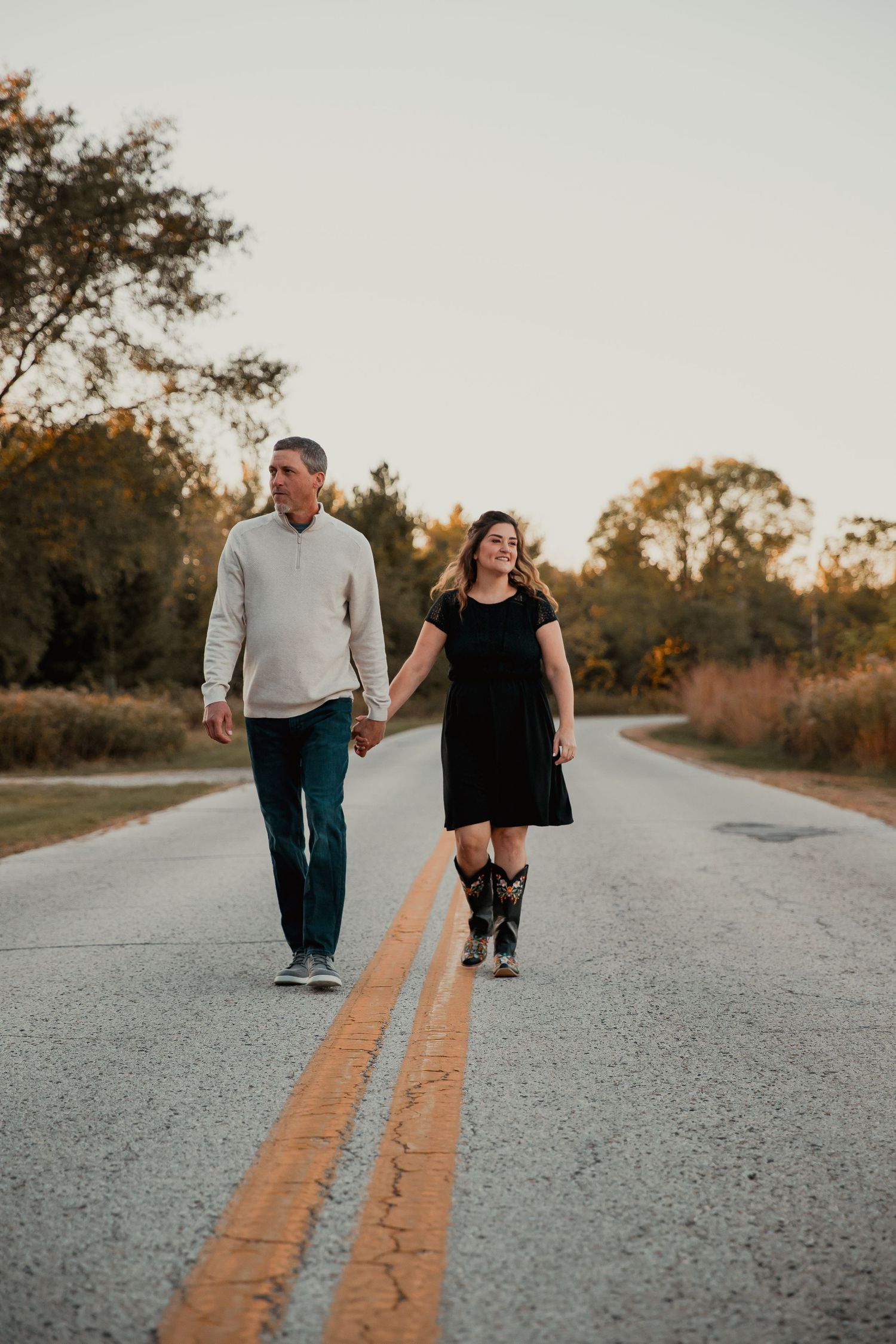 A couple strolls together on a country road with yellow lines. couples engagement