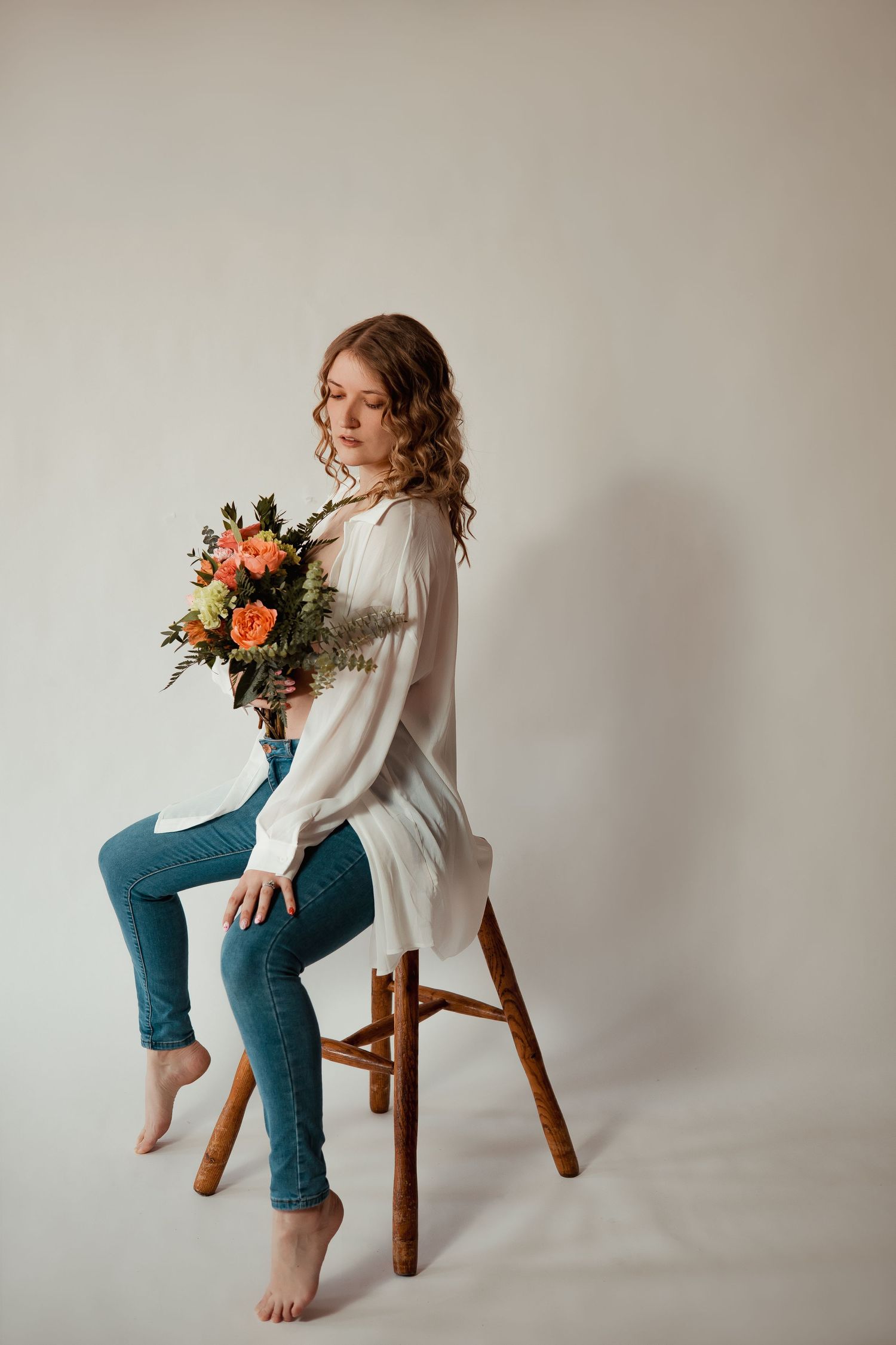 Four artistic portrait shots of a person in blue jeans and white sweater posing with flowers on wooden stool.