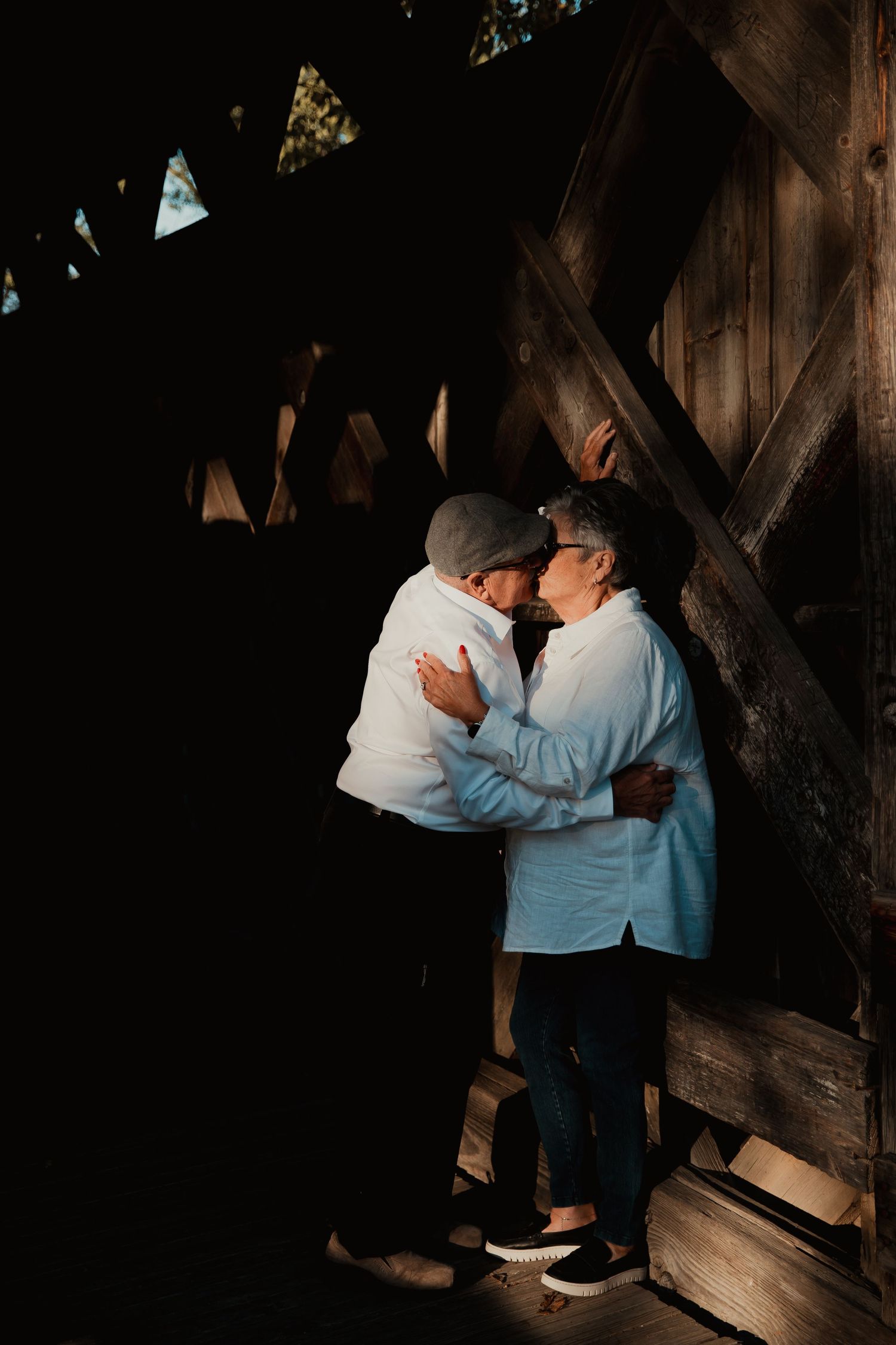 Couple embracing in romantic moment inside dark wooden covered bridge. couples engagement