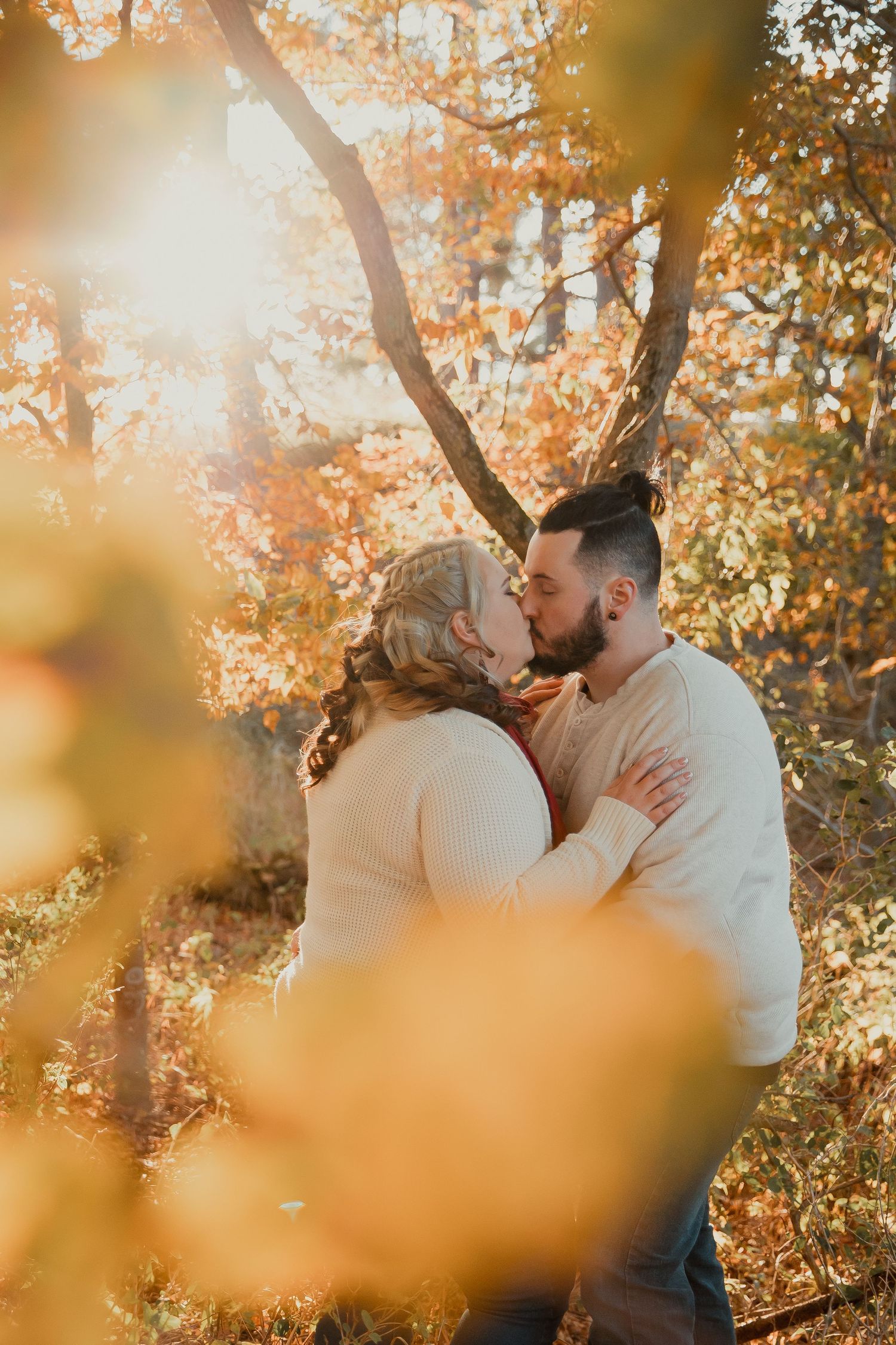 Romantic autumn engagement photo with golden sunlight filtering through fall foliage. couples engagement