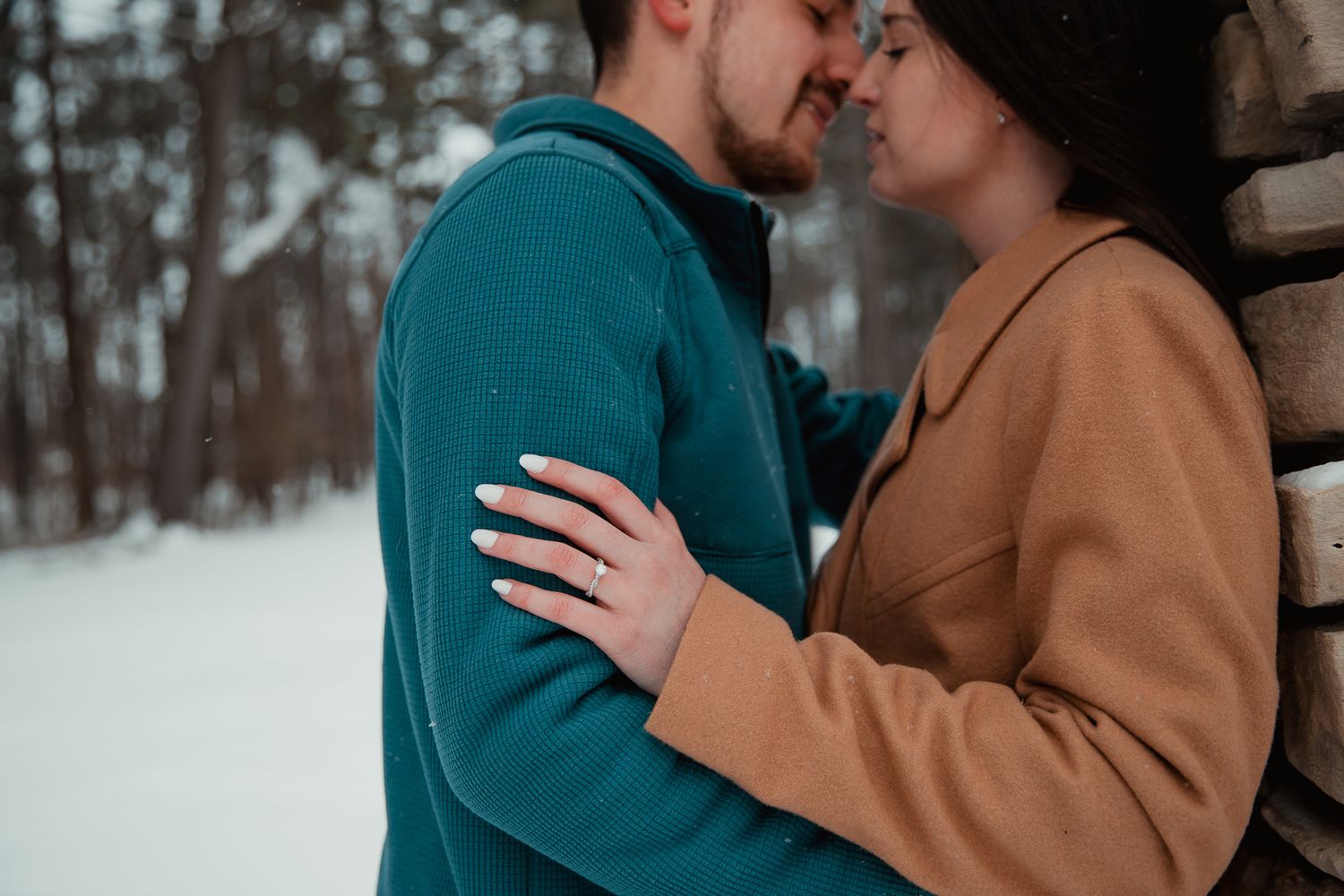 A tender embrace captured in close-up against a snowy winter backdrop. couples engagement