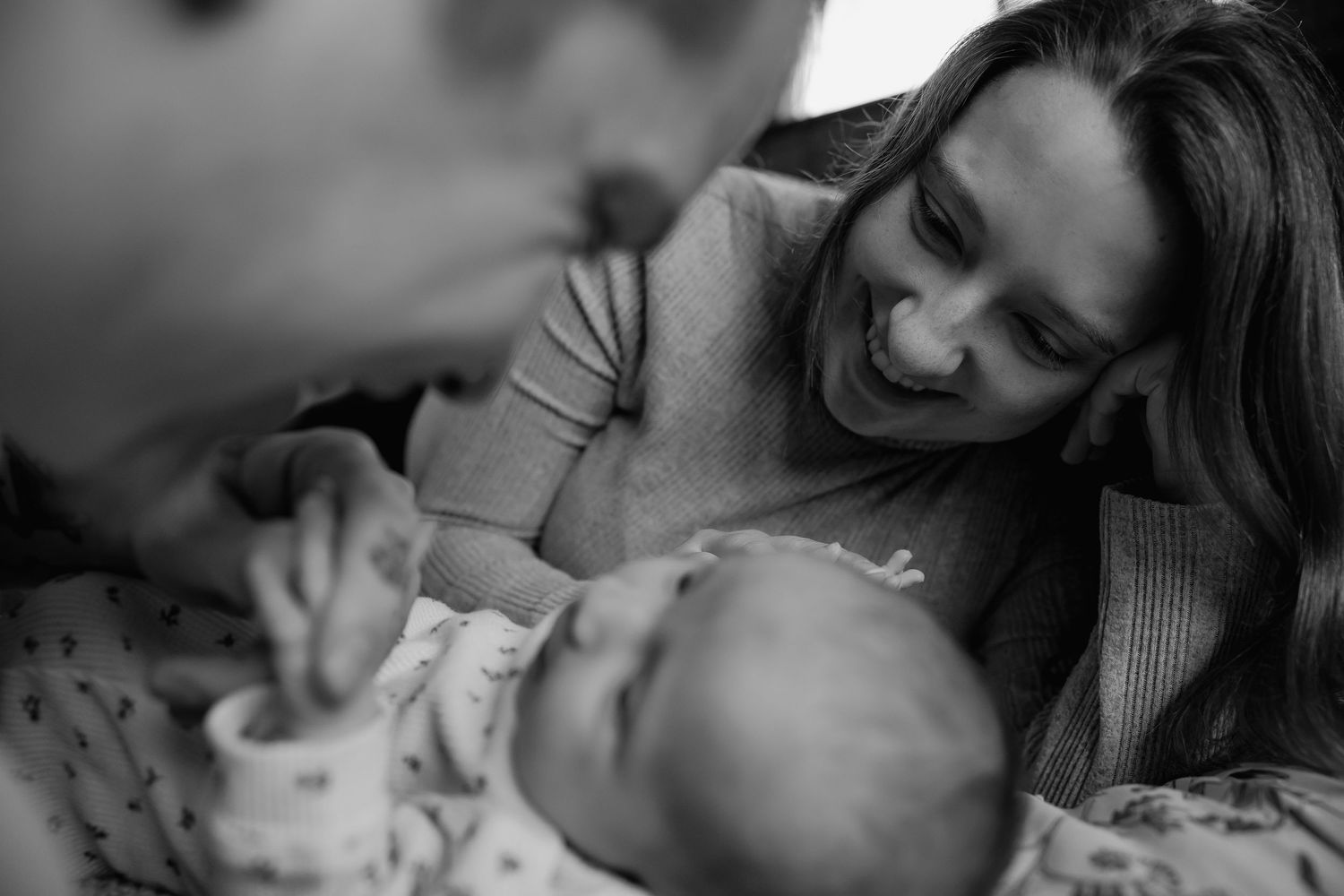 A tender black and white moment between parent and baby as they share a loving interaction on the bed.