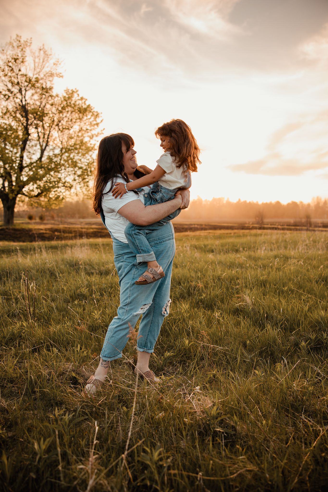 Two people dance together joyfully in a golden sunset meadow wearing matching denim outfits.