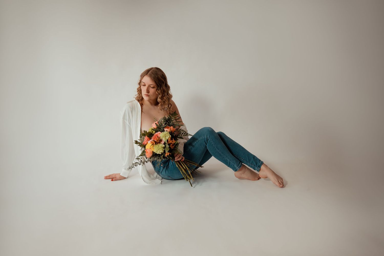 A person in a teal dress lays gracefully on a gray backdrop in an artistic portrait series.