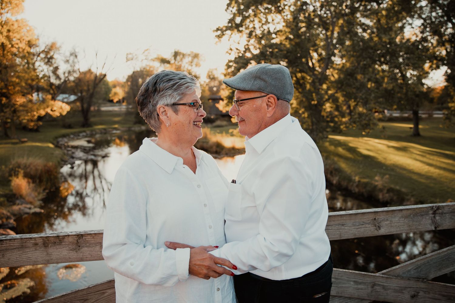 Mature couple embraces on wooden bridge at sunset in romantic outdoor setting. couples engagement