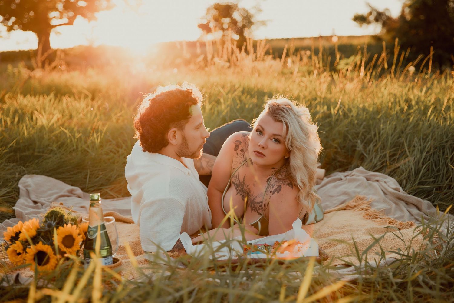Intimate moment between couple during golden hour picnic with sunflowers. couples engagement
